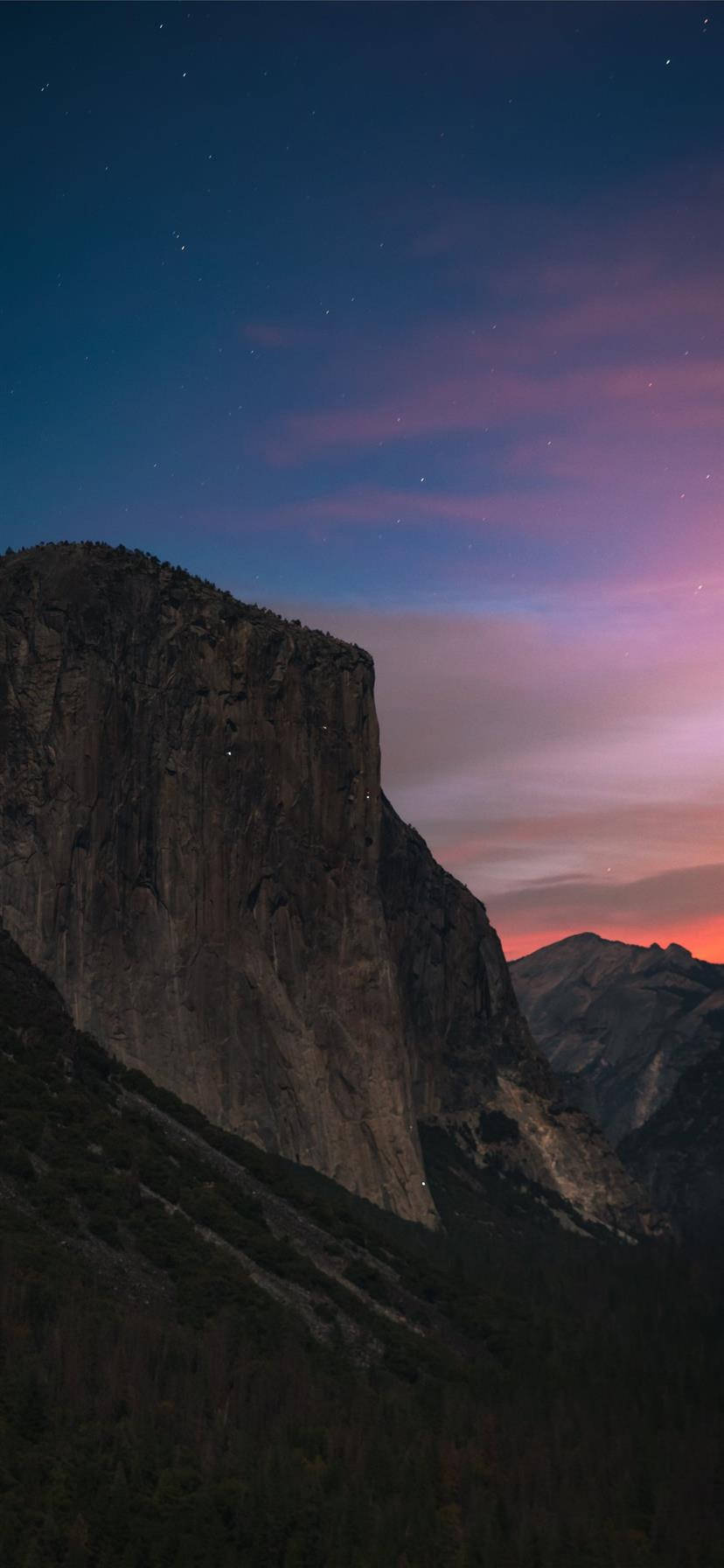 Yosemite iPhone 桌布 壁紙 — 一座高聳的花崗岩懸崖，在佈滿粉紅和紫色雲彩及零星星星的暮色天空中呈現剪影。