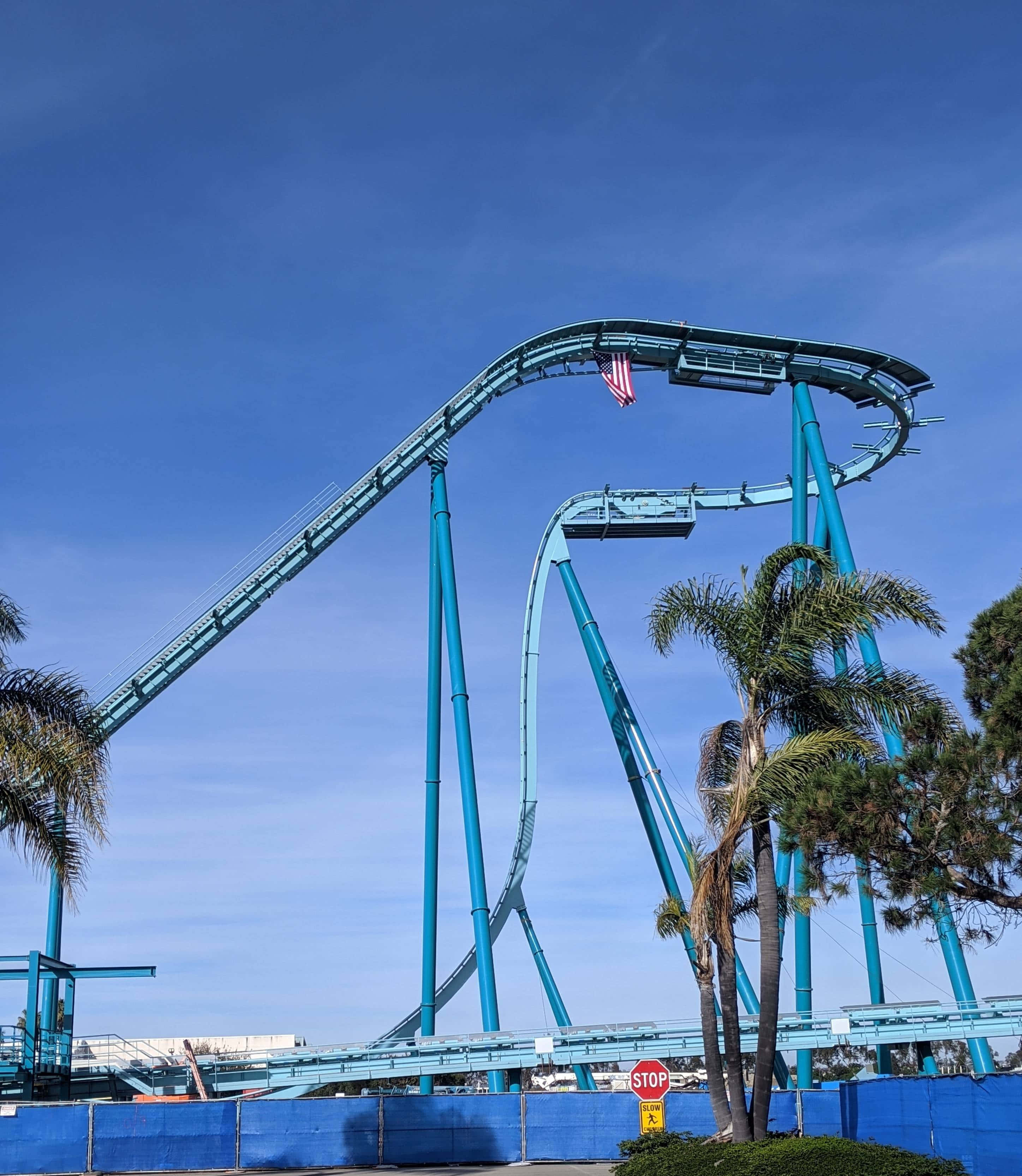 Seaworld 桌布 壁紙 — 一座高聳的藍綠色雲霄飛車在清澈的藍天下蜿蜒，下方棕櫚樹搖曳。