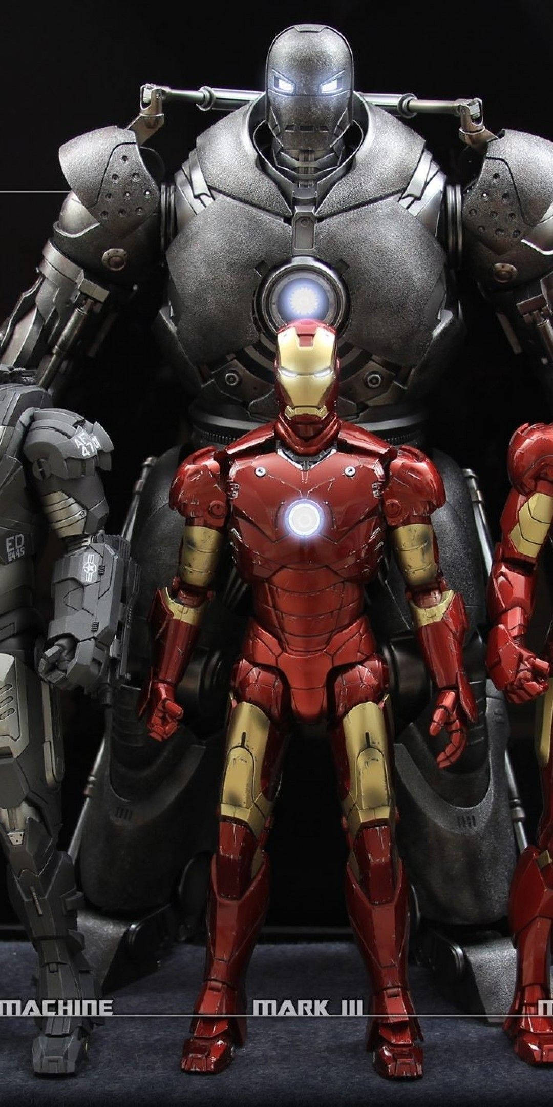 Iron Man Mark 3 桌布 壁紙 — 一座高聳的銀色鋼鐵人 Mark III 裝甲站在一個較小的紅金色鋼鐵人裝甲後面，背景為深色。