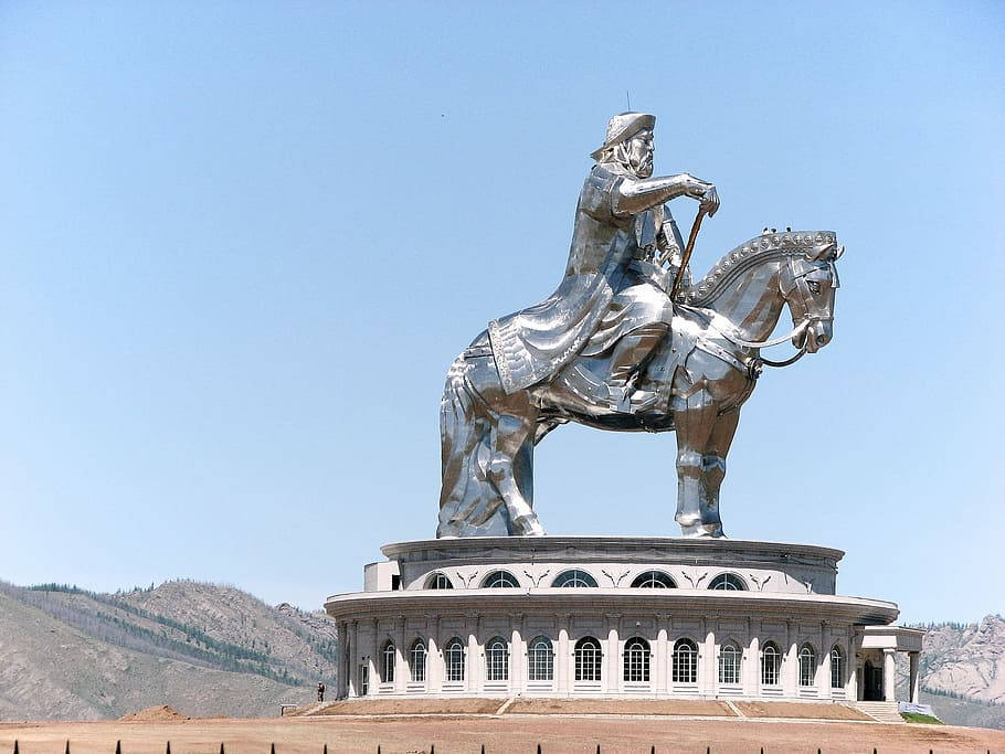 Statue Aesthetic 桌布 壁紙 — 一座高聳的銀色騎馬雕像矗立在巨大的白色基座上，背景是晴朗的藍天和遠處的山脈。