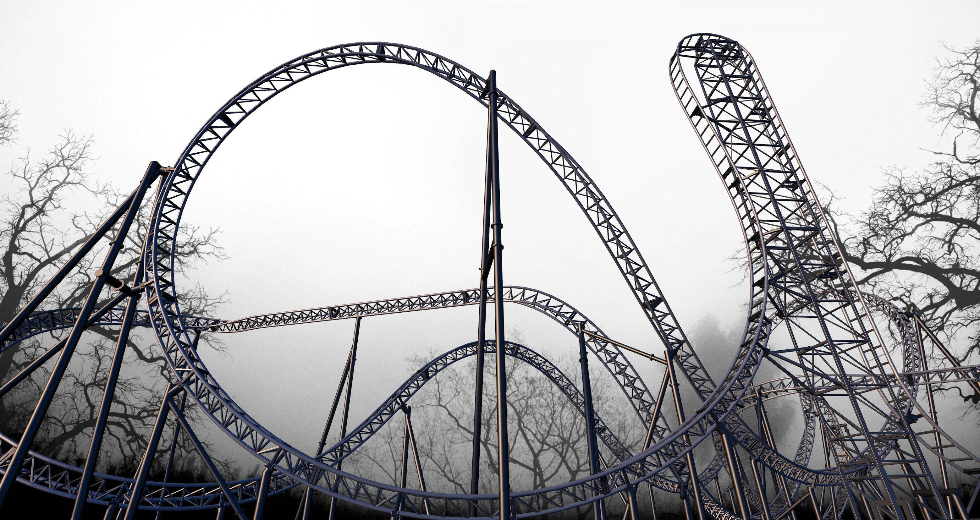 Roller Coaster 桌布 壁紙 — 一座高聳的雲霄飛車在霧氣中蜿蜒穿行，被灰色天空下光禿的冬日樹木環繞。
