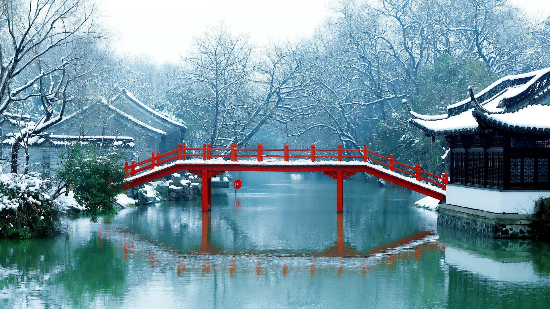 Suzhou 桌布 壁紙 — 一座鮮紅色的拱橋橫跨平靜的雪運河，在霧濛濛的冬日天空下映照出傳統東亞建築。