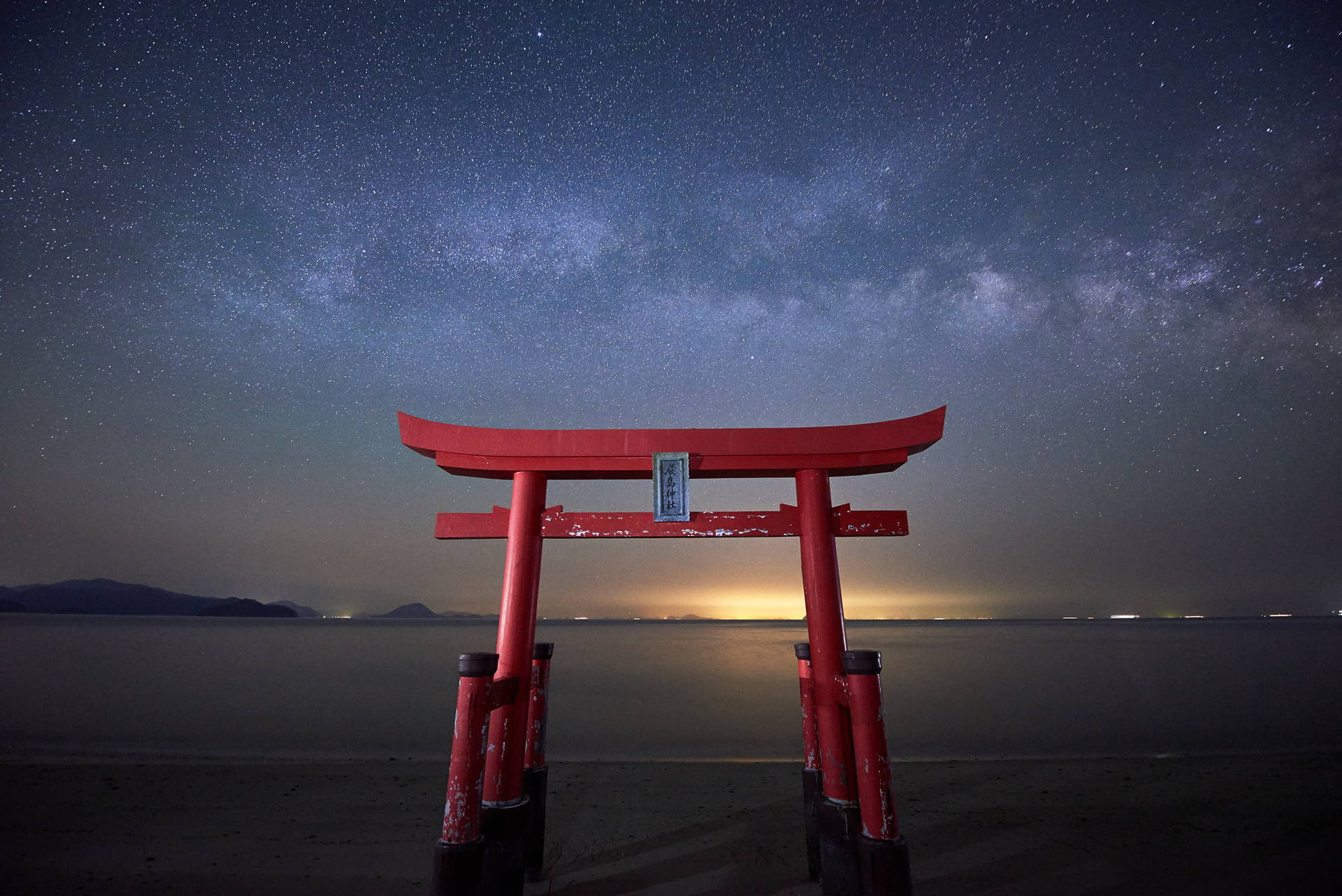 沙灘上星空下的紅色鳥居，帶有銀河