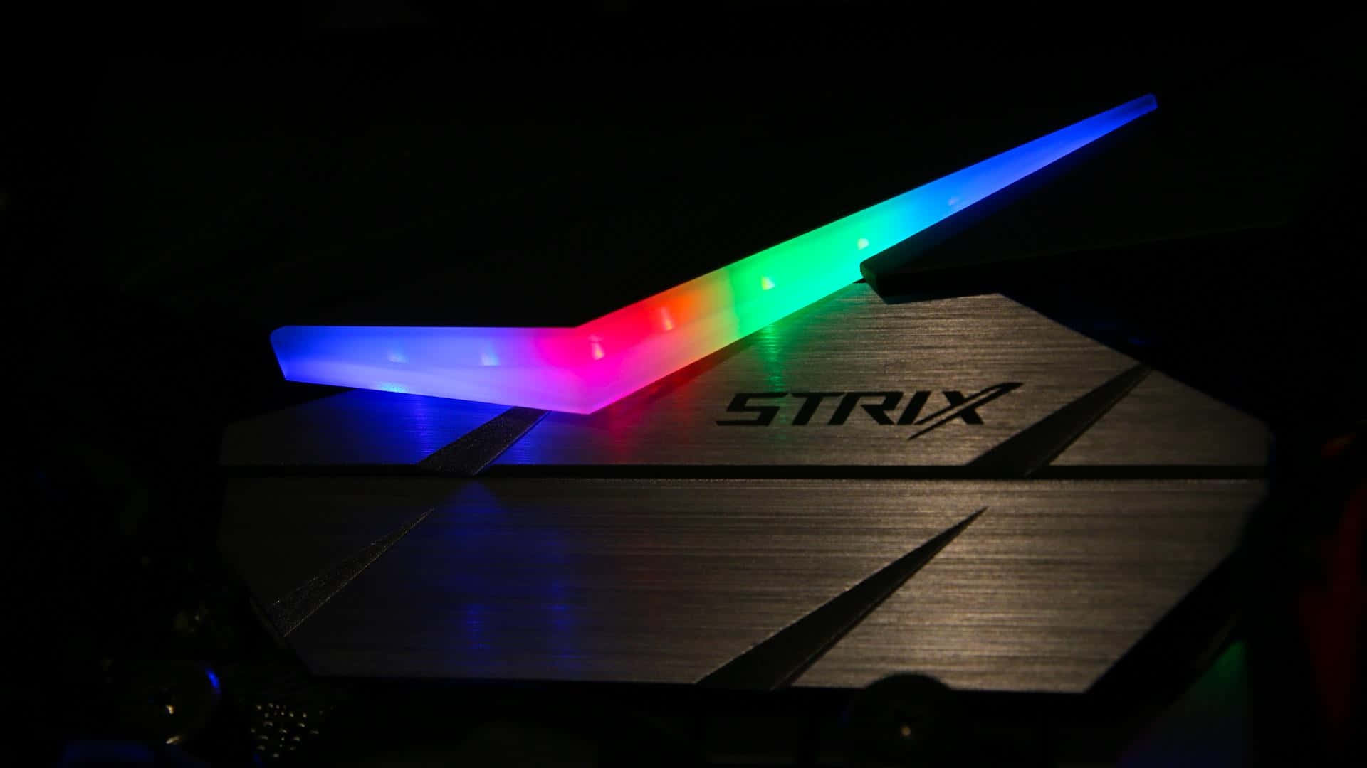 RGB 桌布 壁紙 — 一張 Strix 顯示卡帶有鮮豔的彩虹 LED 燈光，在黑暗背景下發光。