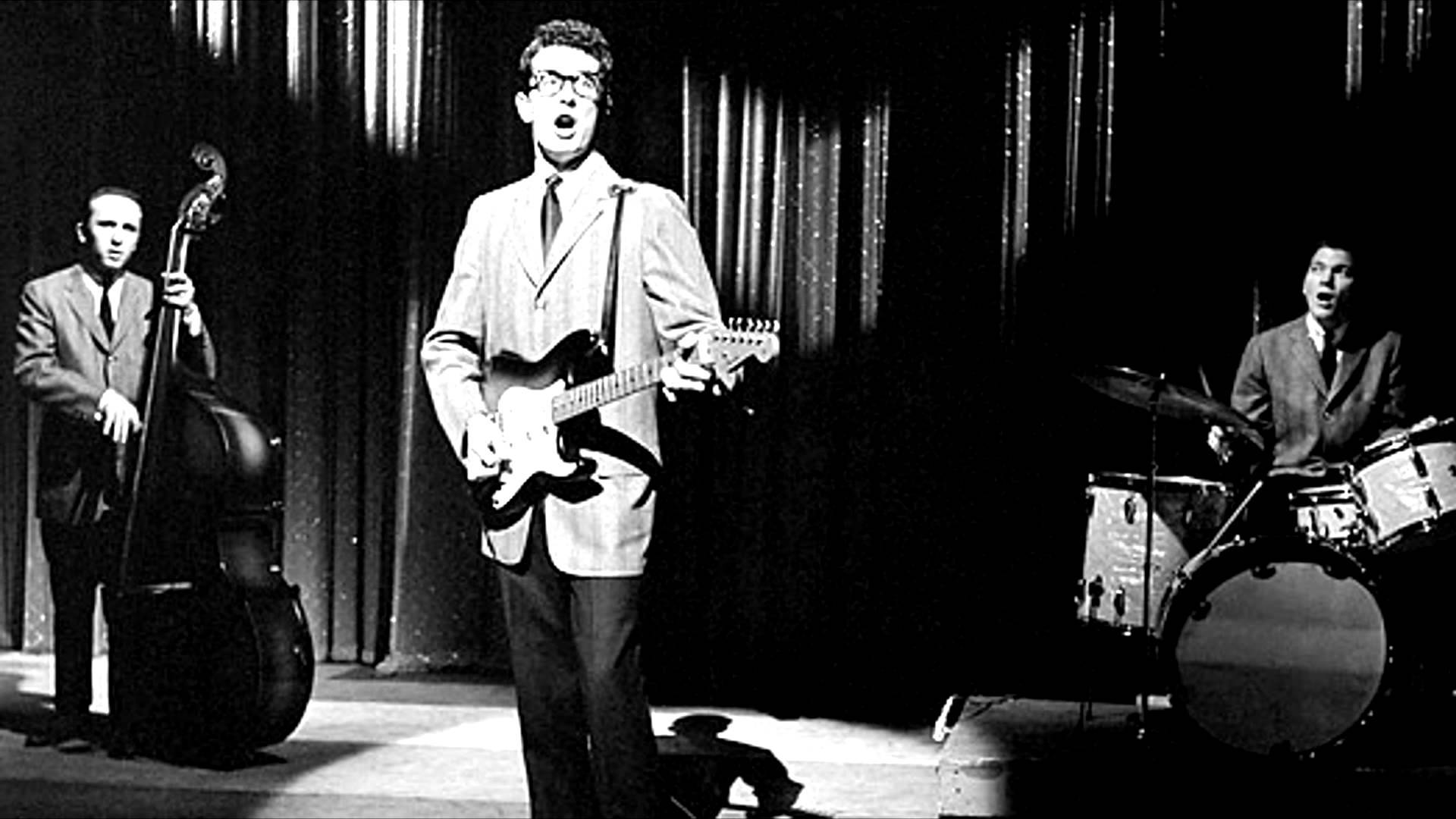Rock 桌布 壁紙 — 一張1950年代樂團在舞台上表演的黑白照片，包括吉他手、歌手、貝斯手和鼓手，在戲劇性的舞台燈光下。
