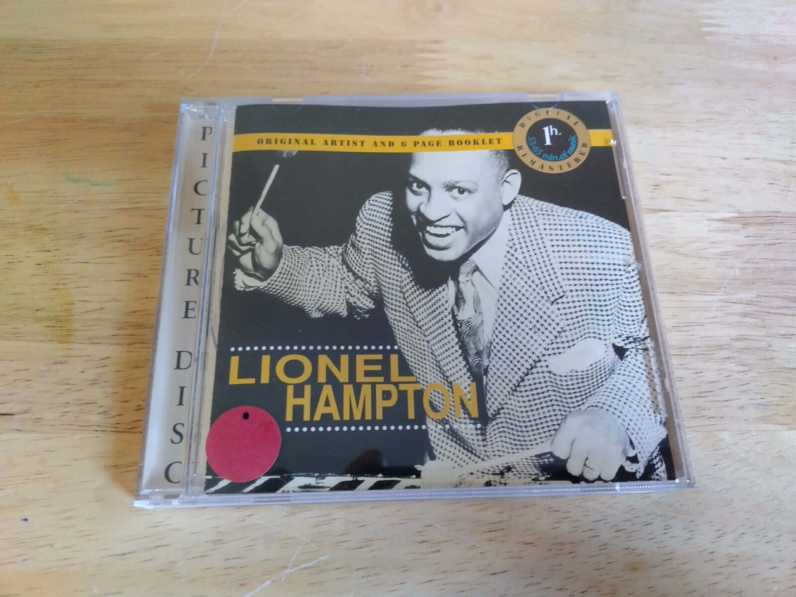 音樂 桌布 壁紙 — 一張Lionel Hampton微笑握住鼓棒的復古圖案CD放在淺色木質表面上。
