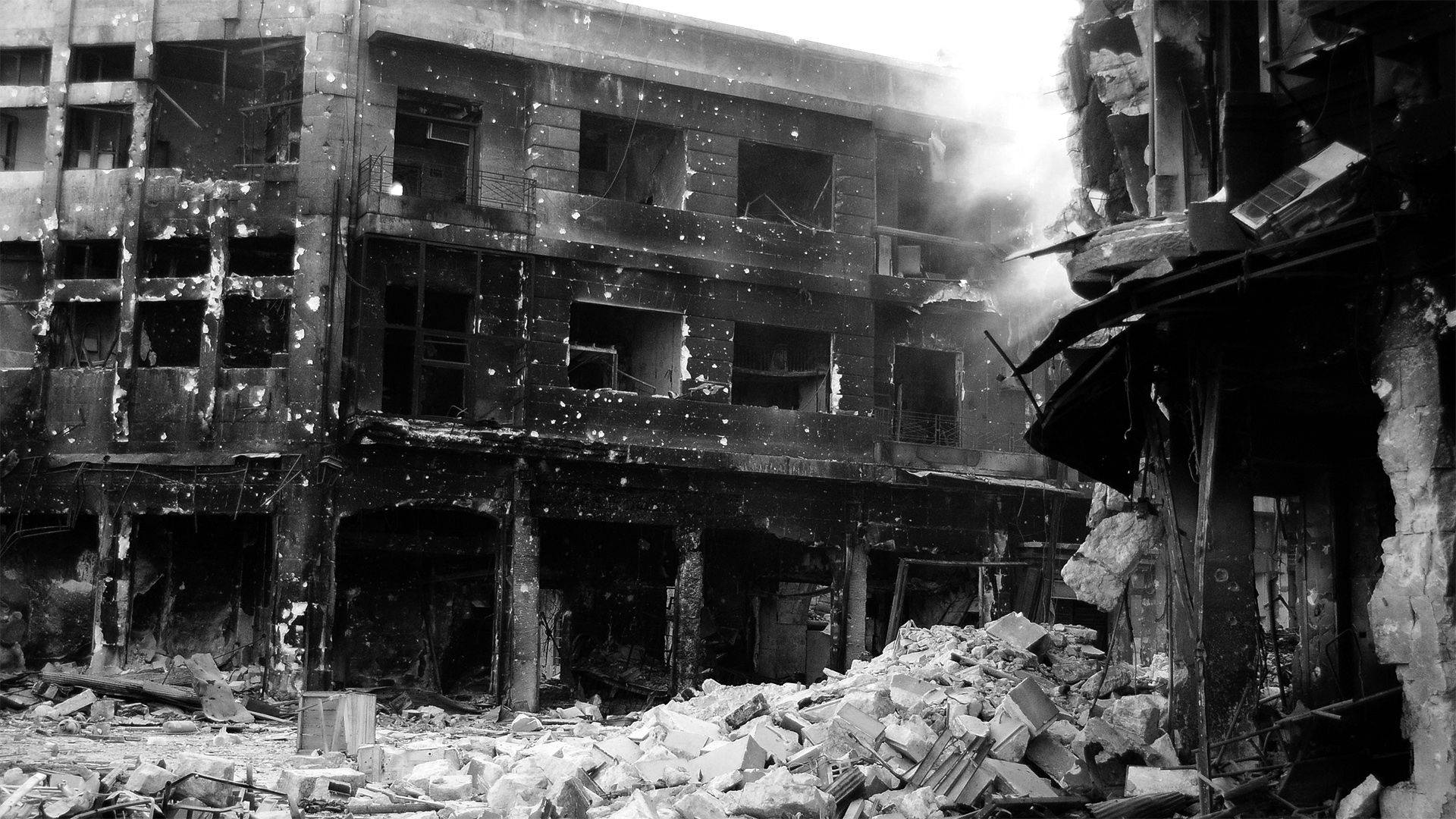 Syria 桌布 壁紙 — 一張令人毛骨悚然的黑白照片，顯示一棟嚴重受損的多層建築，窗戶破碎，地面佈滿瓦礫。