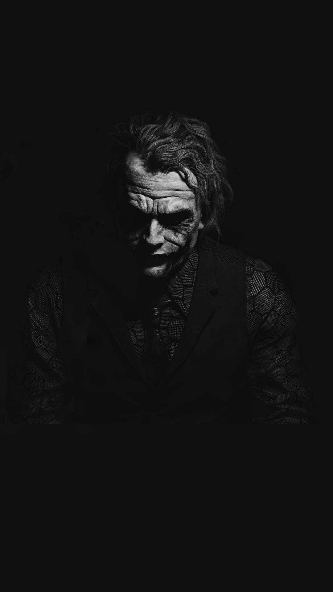 Dark Joker 桌布 壁紙 — 一張令人難忘的黑白小丑肖像，在黑暗背景中露出邪惡的笑容。