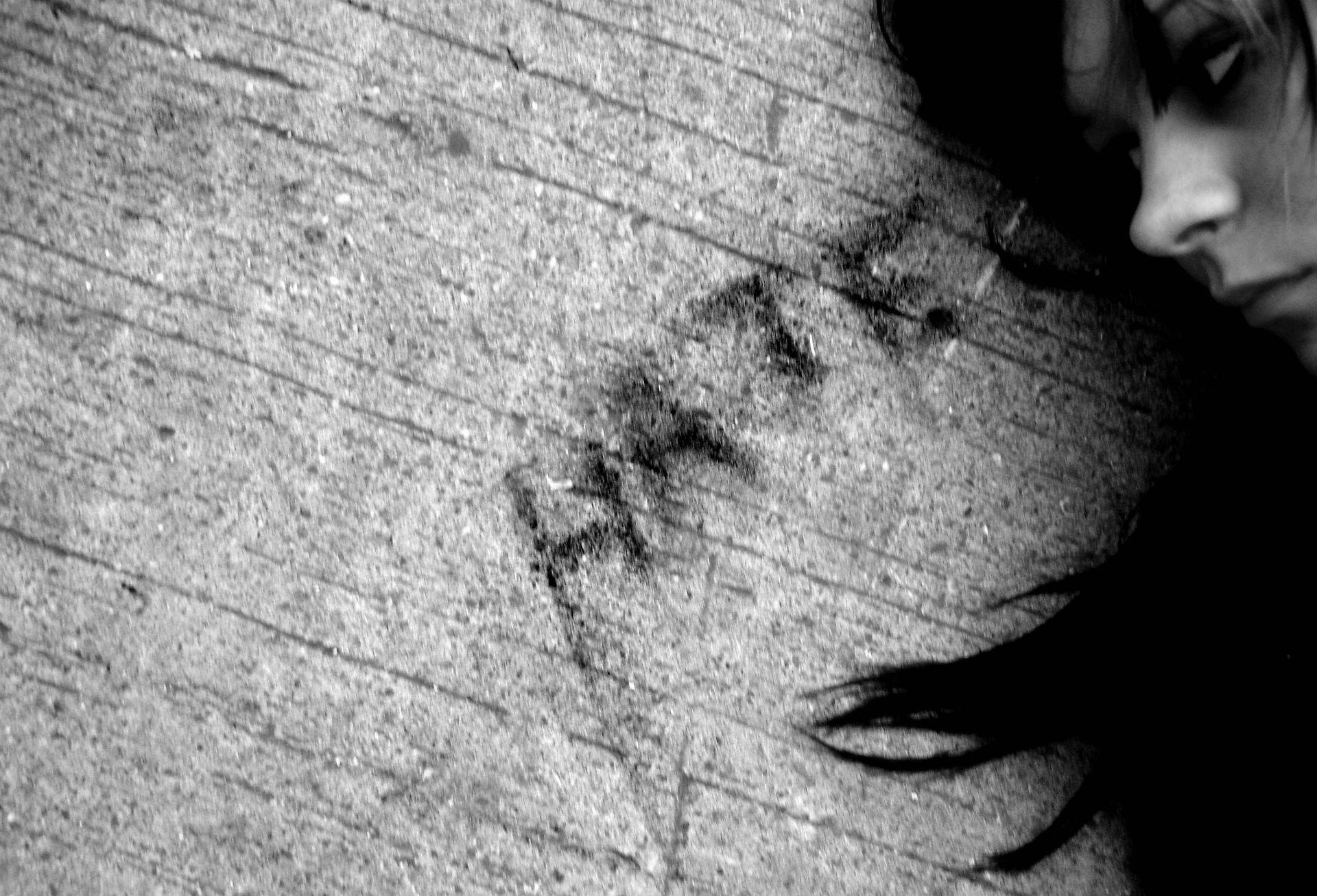 emo 桌布 壁紙 — 一張令人難忘的黑白特寫，女人的臉靠在一面帶有模糊塗鴉的粗糙混凝土牆上。