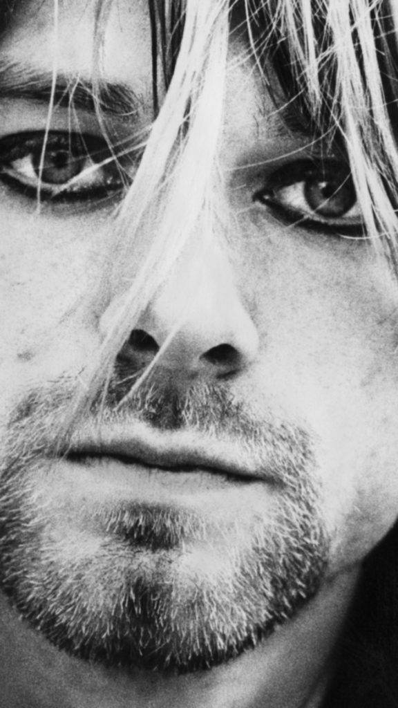 Cobain 桌布 壁紙 — 一張令人難忘的黑白特寫，捕捉了男人被凌亂頭髮和鬍渣襯托的銳利眼神。