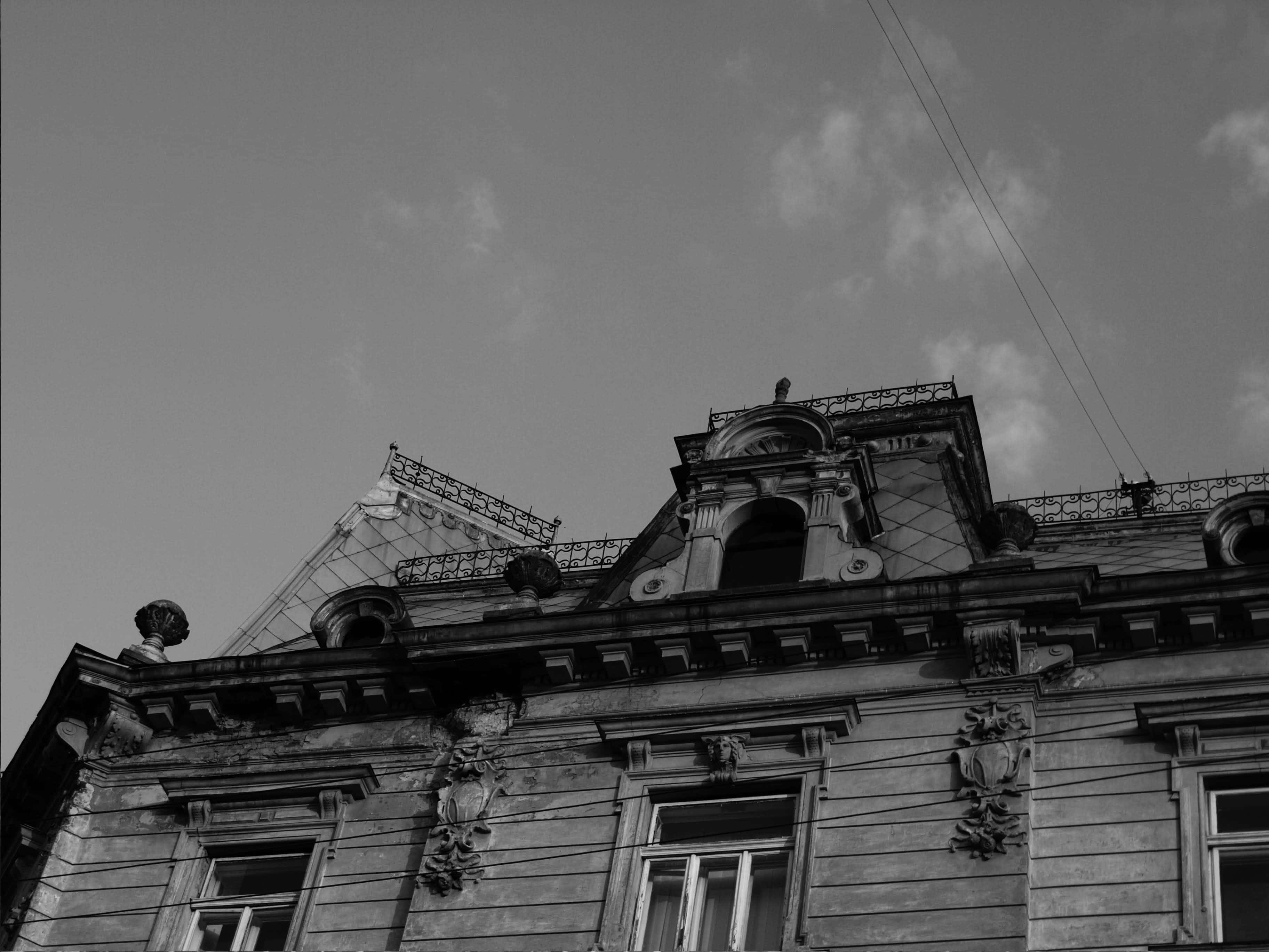 Aesthetic Black And White 桌布 壁紙 — 一張以低角度拍攝的戲劇性黑白照片，展示一座華麗且風化的建築立面，背景是陰雲密佈的天空。