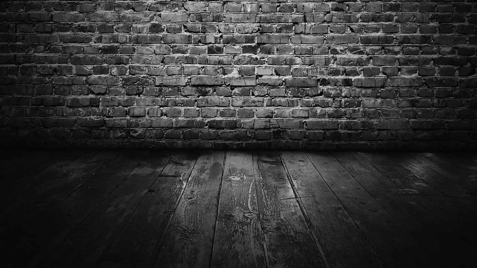 Dark Wall 桌布 壁紙 — 一張充滿氛圍的黑白照片，展示一個空房間，內有風化的磚牆和深色木地板。