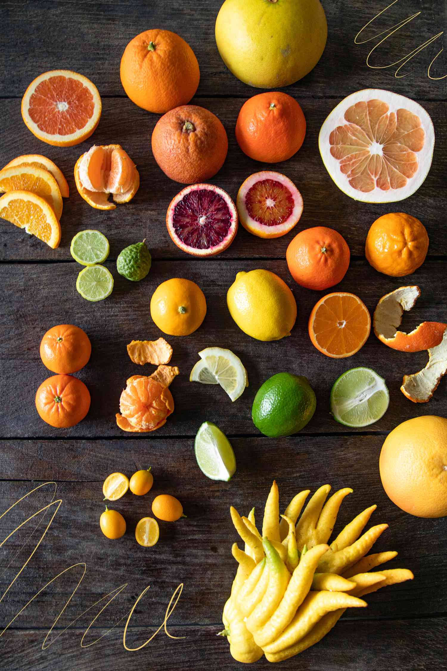 Fruits 桌布 壁紙 — 一張充滿活力的俯拍照片，展示了各種柑橘類水果，包括柳橙、血橙、檸檬、萊姆和金桔，排列在深色木質表面上。