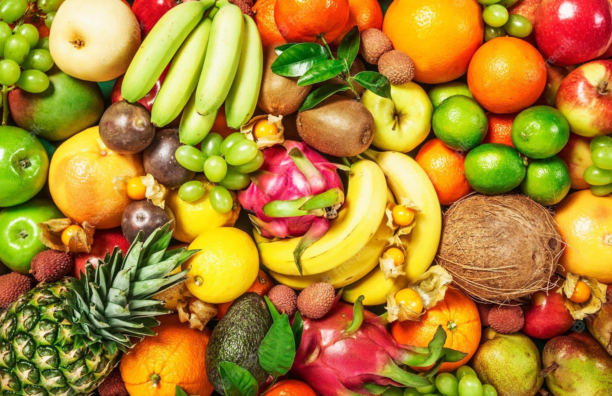 Fruit 桌布 壁紙 — 一張充滿活力的俯拍照片，展示了香蕉、鳳梨和火龍果等各種熱帶和溫帶水果堆疊在一起。