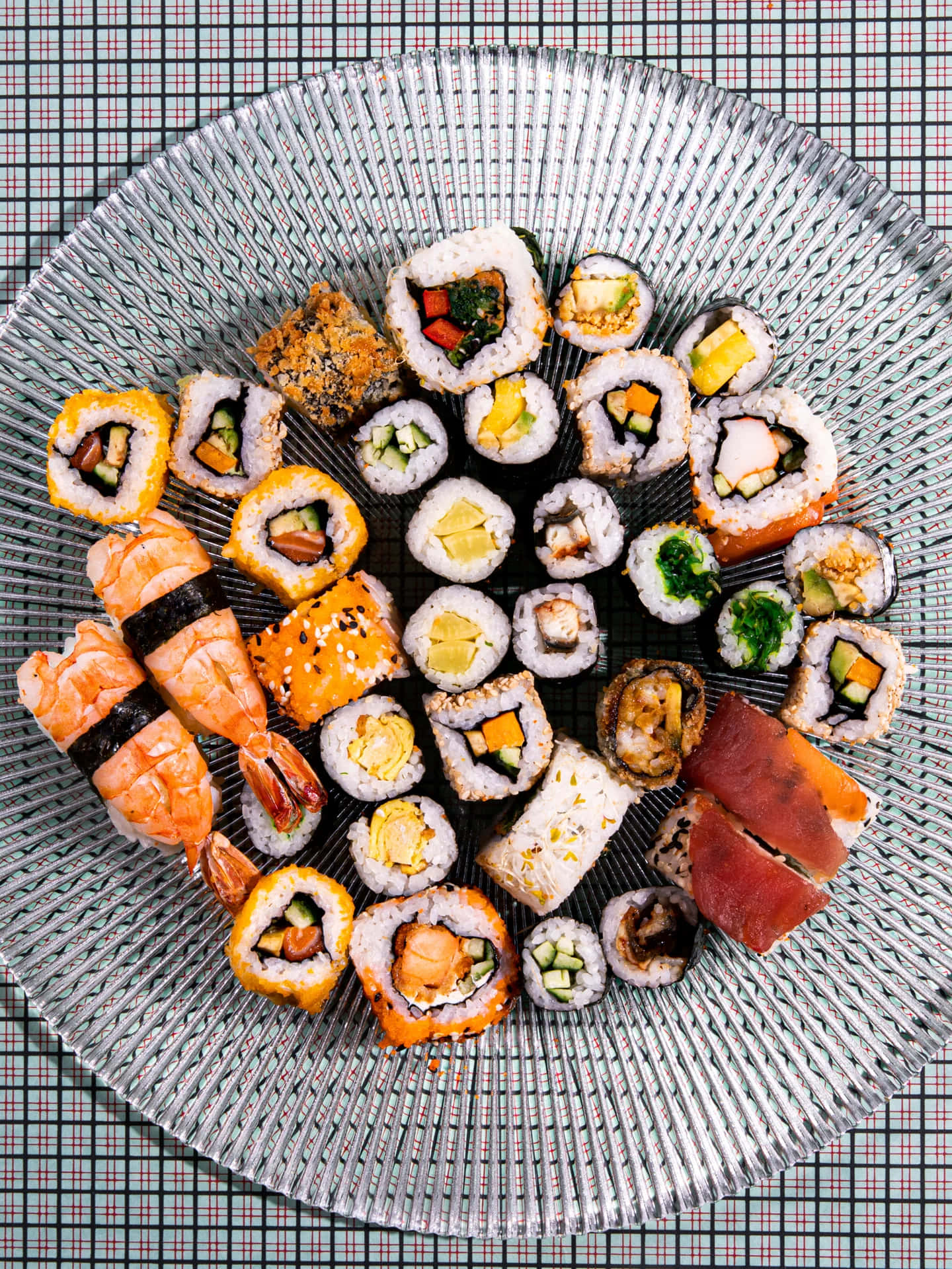 Food Table 桌布 壁紙 — 一張充滿活力的俯拍照片，展示各種壽司卷和握壽司，藝術地擺放在有紋理的玻璃盤上。