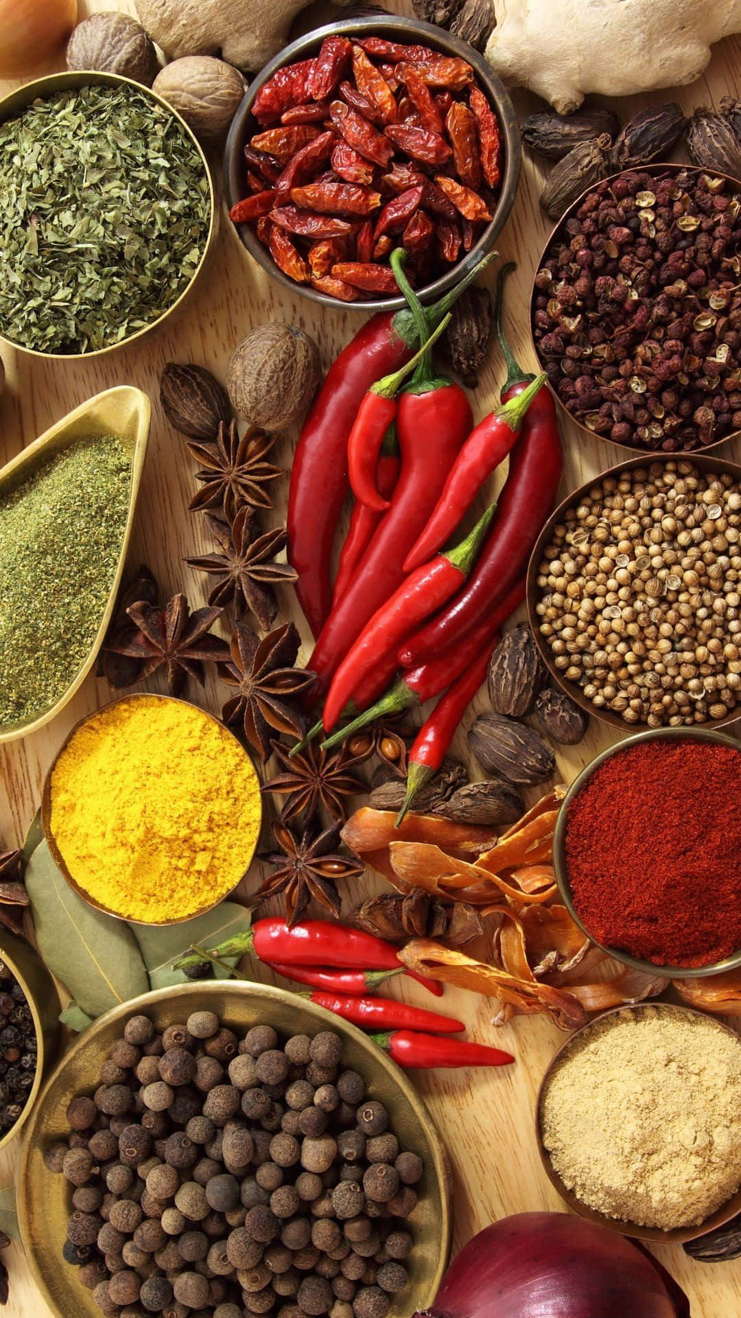 pepper 桌布 壁紙 — 一張充滿活力的俯拍照片，展示各種香料和香草，如紅辣椒、薑黃和胡椒粒，整齊排列在木質表面上。