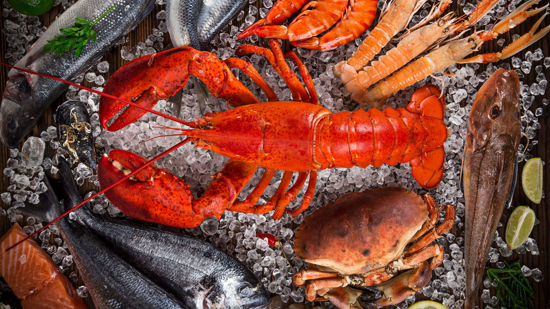 Lobster 桌布 壁紙 — 一張充滿活力的俯拍照片，展示新鮮海鮮，包括龍蝦、螃蟹、蝦和魚，擺放在碎冰上，配以萊姆角和香草。