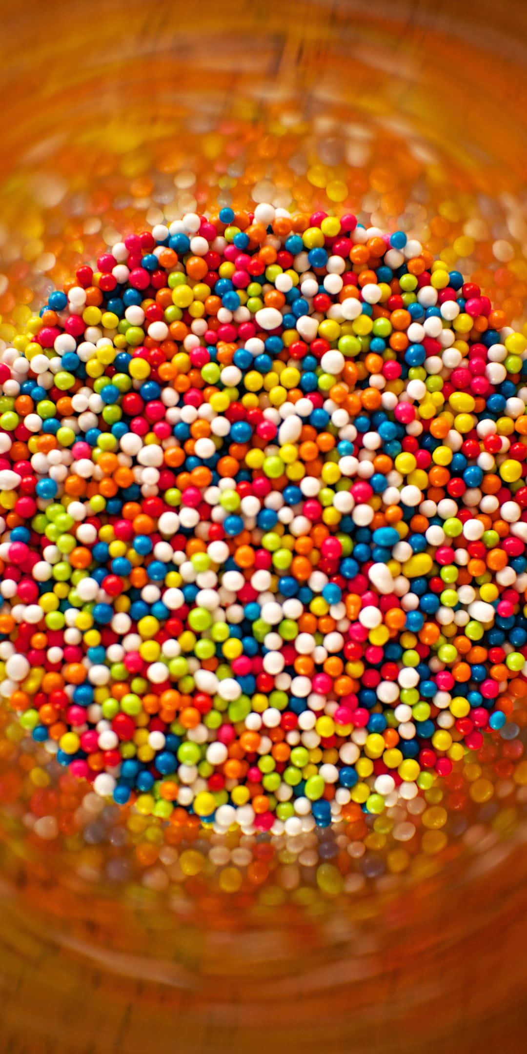 Sprinkles 桌布 壁紙 — 一張充滿活力的俯拍照片，淺景深下彩色糖珠從木碗中溢出。