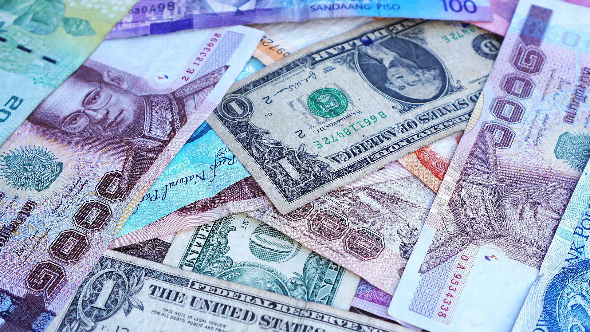 Money 桌布 壁紙 — 一張充滿活力的特寫照片，展示散落的國際紙幣，包括美元和菲律賓比索。