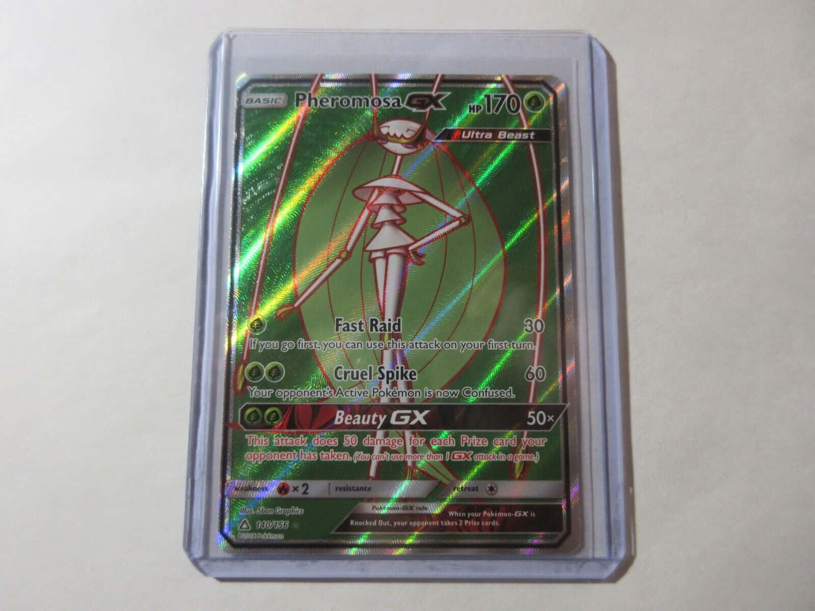 任天堂 桌布 壁紙 — 一張全息 Pheromosa GX 寶可夢卡，放在透明保護套中，置於純白表面。