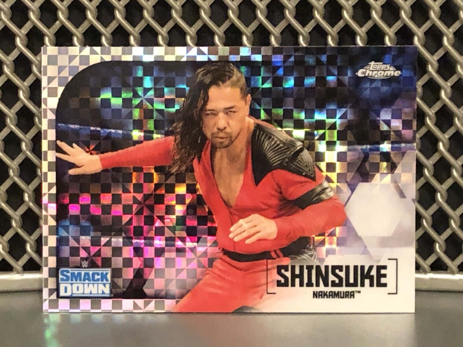 WWE 桌布 壁紙 — 一張全息WWE交易卡，展示身穿紅色服裝的中邑真輔，在棋盤格彩虹背景前動感擺姿。