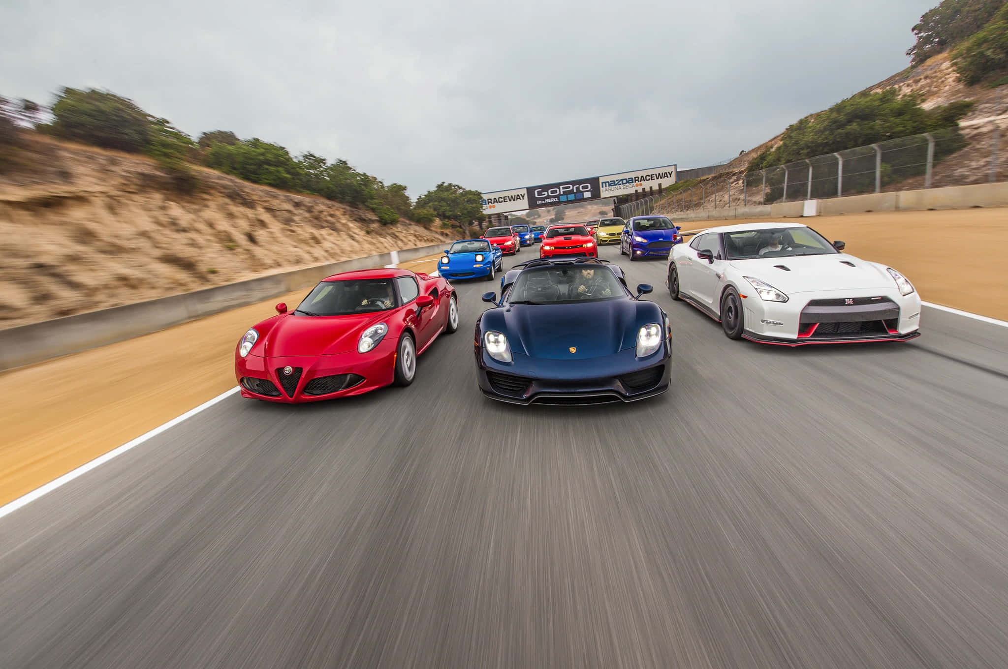 Car Racing 桌布 壁紙 — 一張動態拍攝的豪華跑車在蜿蜒賽道上奔馳的照片，帶有動態模糊和陰天效果。