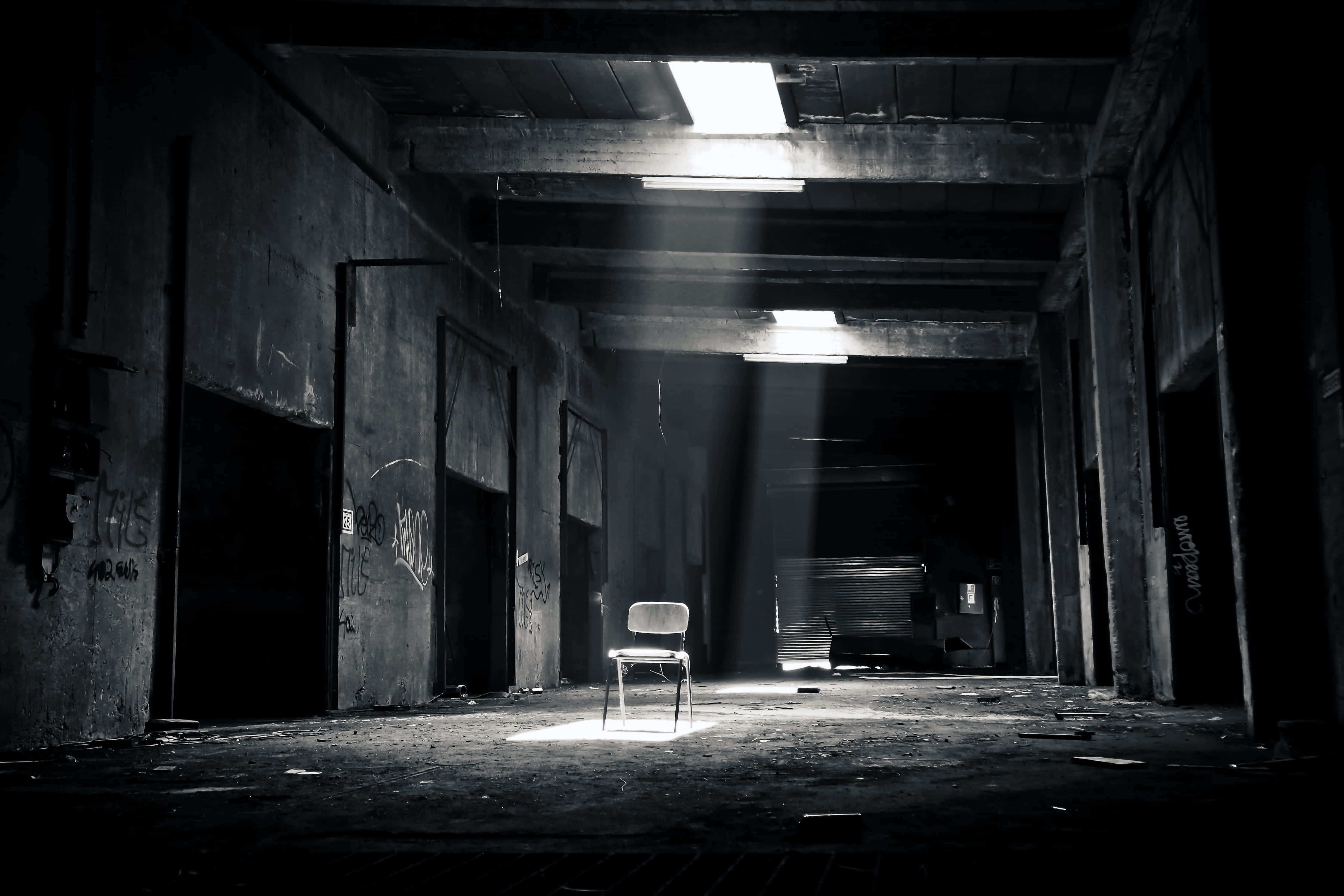 Empty Room 桌布 壁紙 — 一張單椅放在昏暗廢棄的倉庫中，沐浴在從上方射下的強烈光束中。