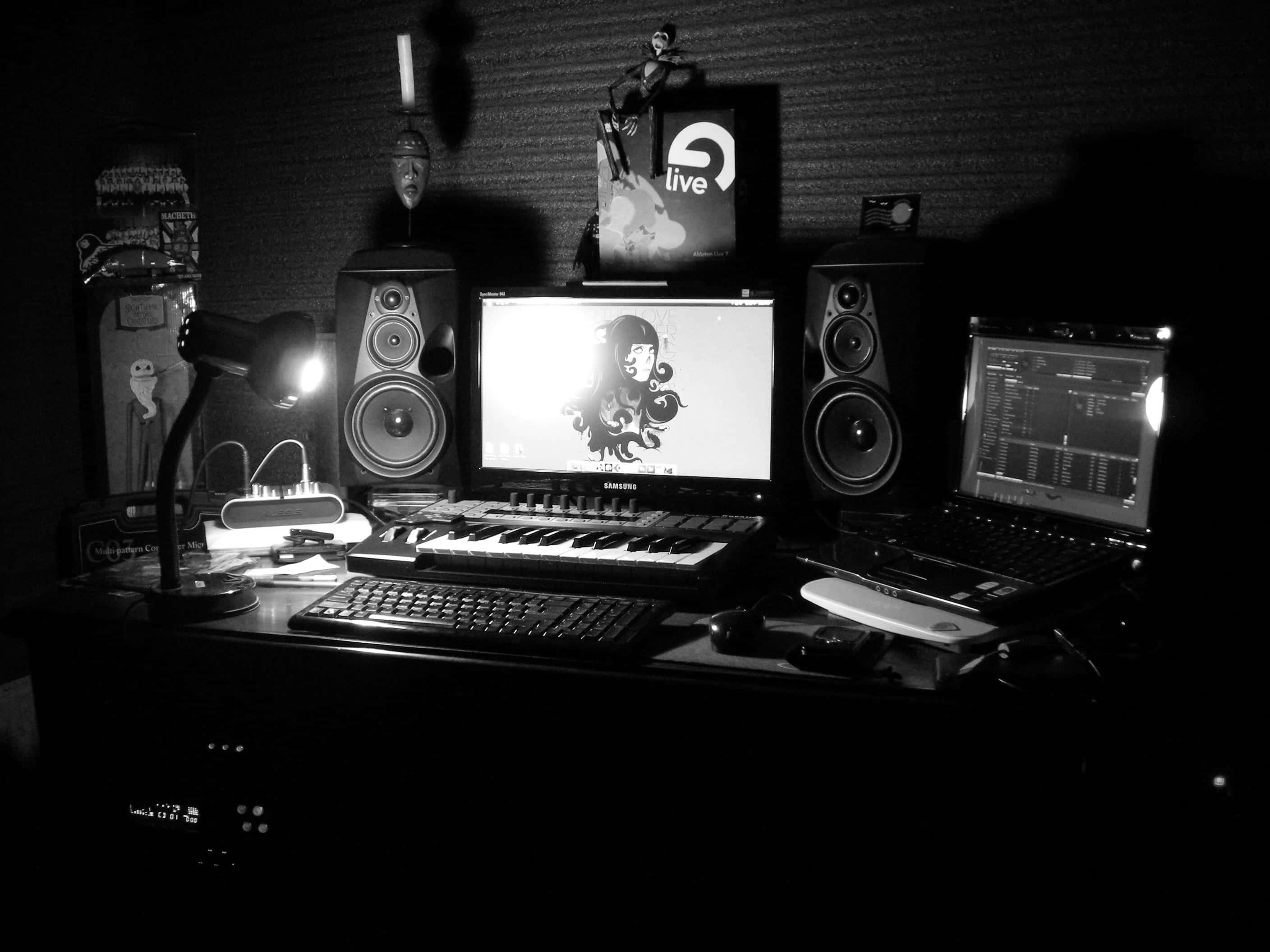 Fl Studio 桌布 壁紙 — 一張單色拍攝的昏暗音樂製作站，發光的螢幕和揚聲器投下陰影。