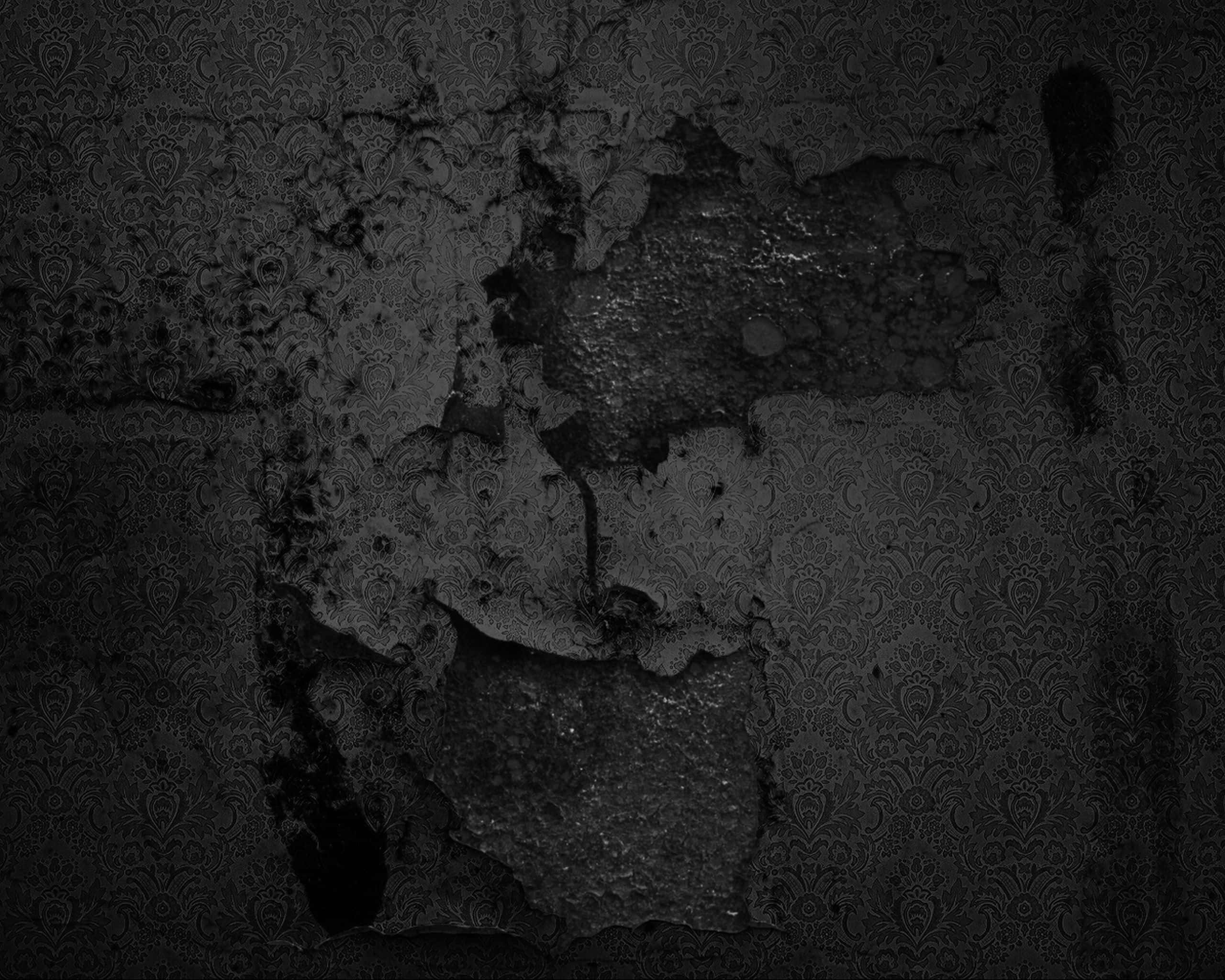 wall 桌布 壁紙 — 一張單色特寫，剝落的華麗壁紙露出下方粗糙紋理的牆壁，處於深色陰影中。