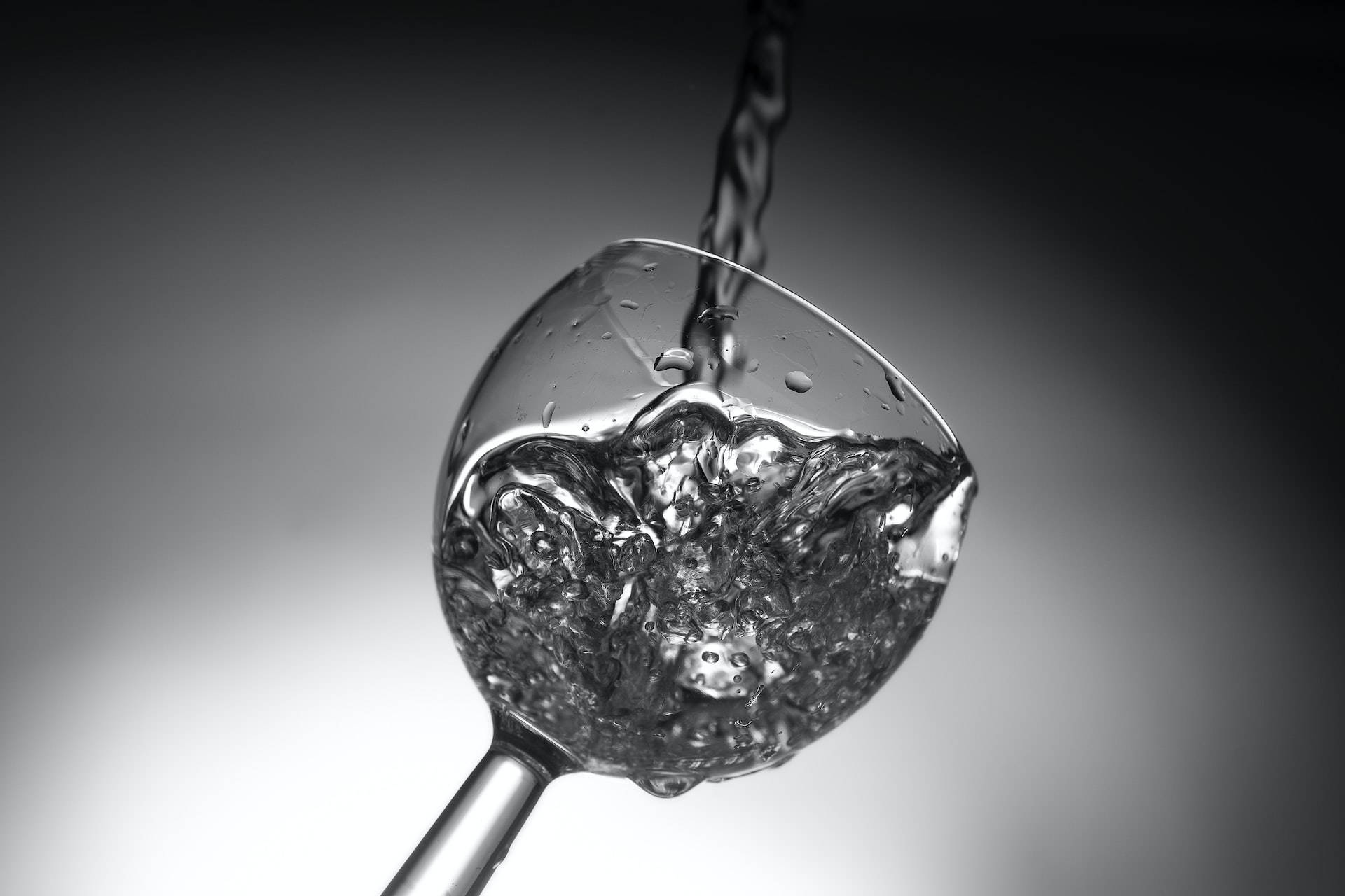 glass 桌布 壁紙 — 一張單色特寫捕捉了水動態地倒入玻璃杯中，在柔和的漸變背景上產生閃閃發光的氣泡和水滴。