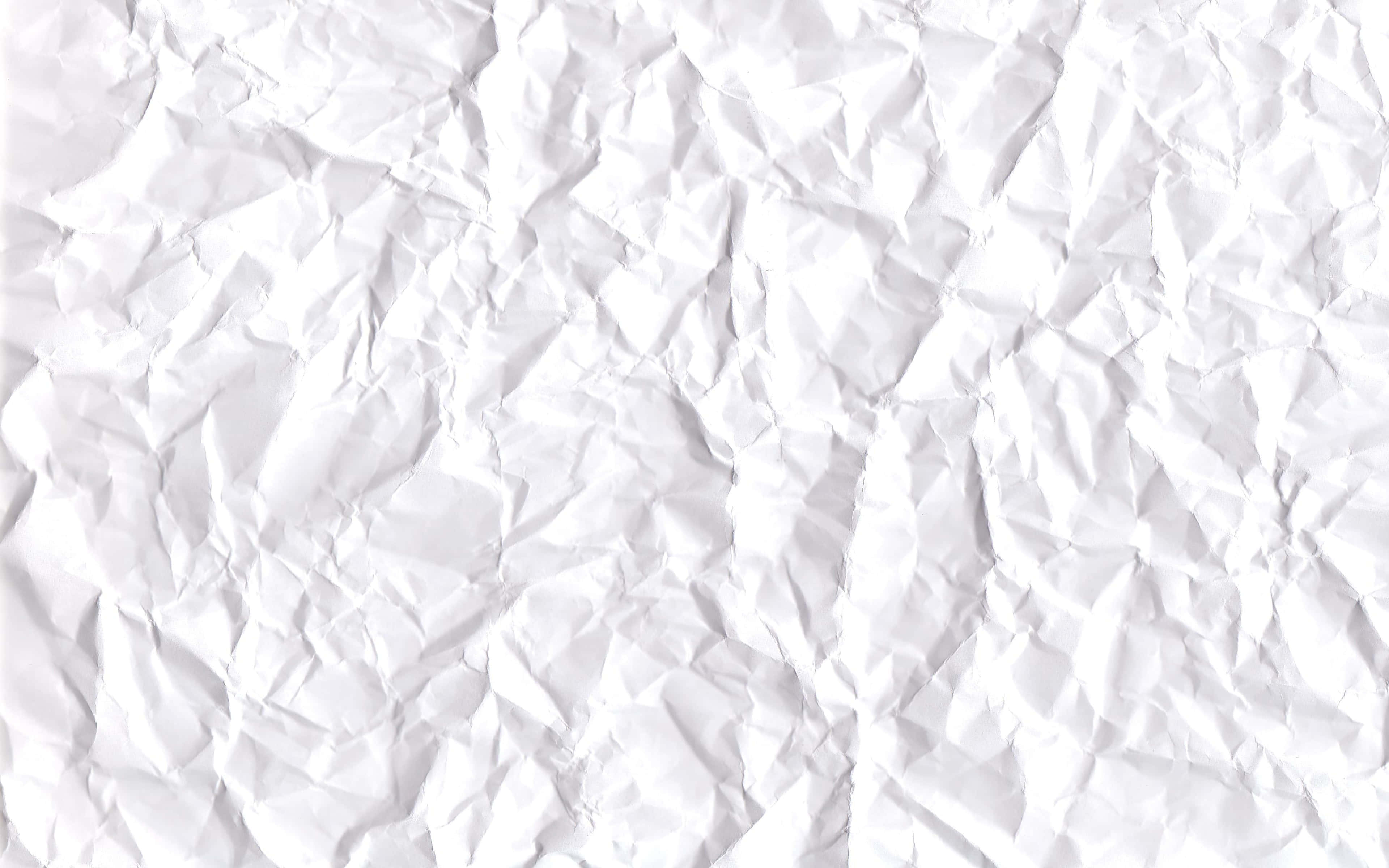 White Texture 桌布 壁紙 — 一張嚴重皺摺的白紙特寫，深色陰影和明亮高光營造出紋理表面。