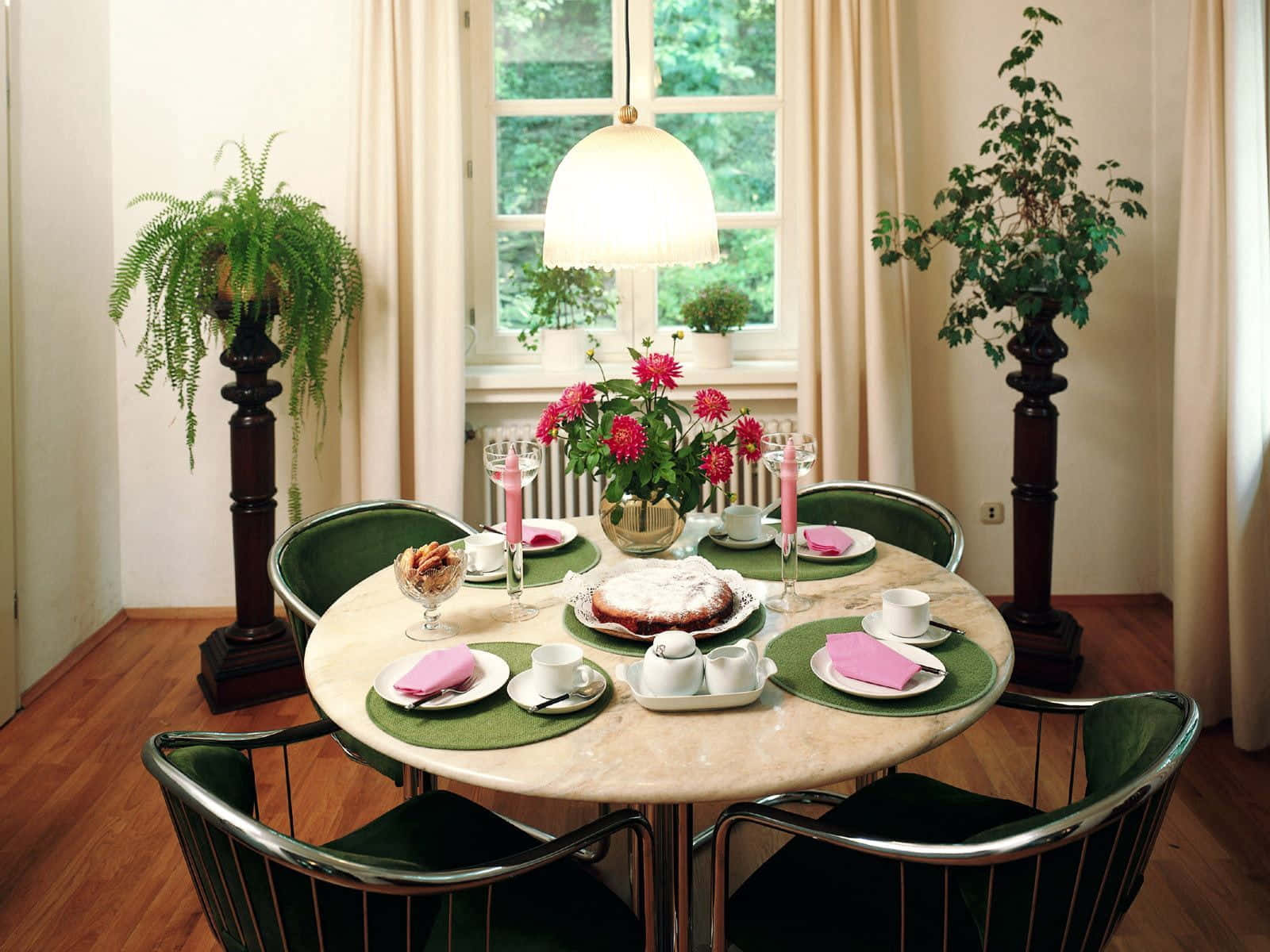 Dining Room 桌布 壁紙 — 一張圓形大理石餐桌，擺設了茶具，配有粉紅色餐巾和花卉中心裝飾，下方是一盞發光的吊燈。