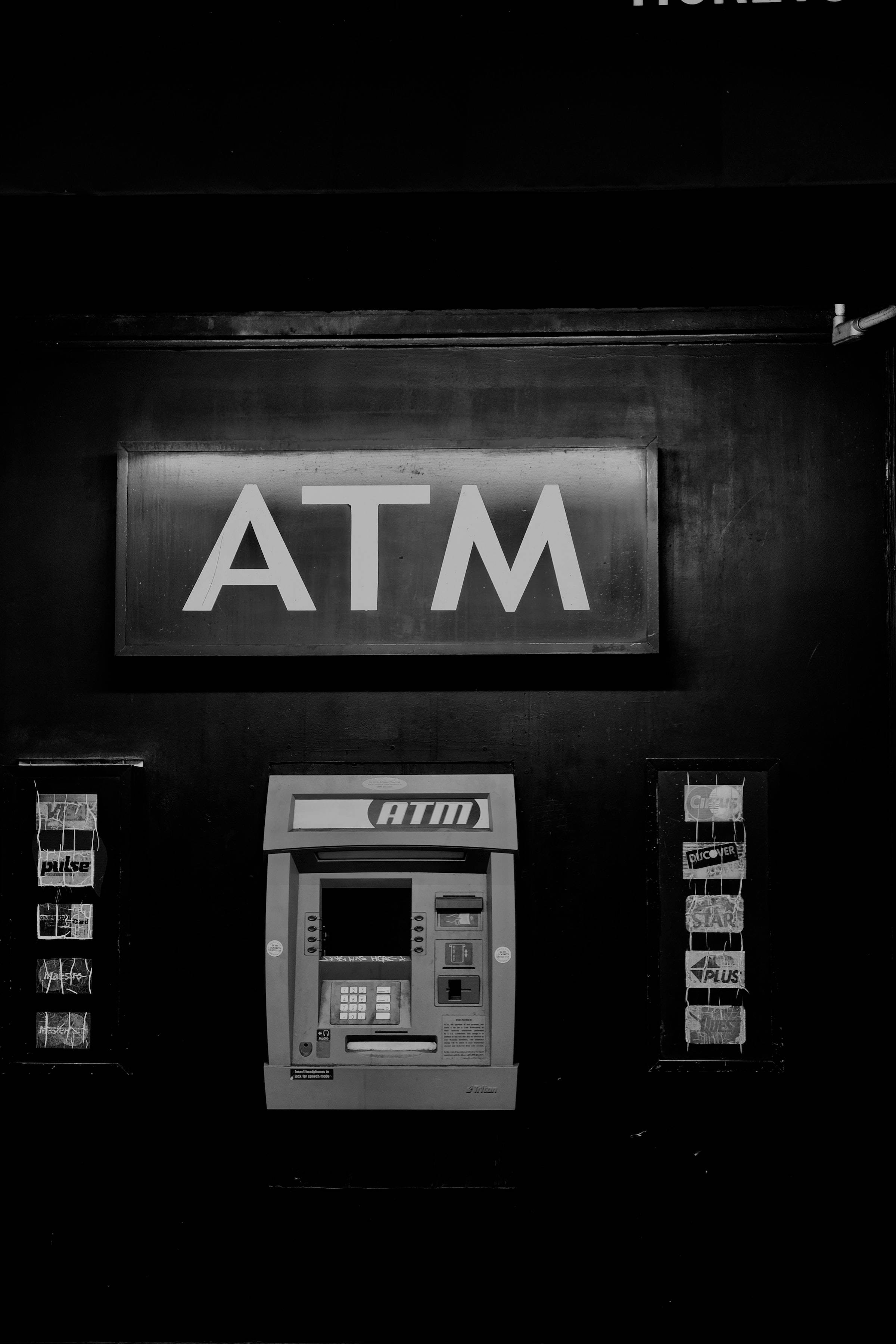 atm 桌布 壁紙 — 一張在昏暗空間中、發光標誌下的自動櫃員機的鮮明黑白照片。