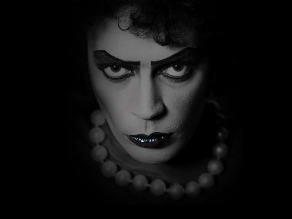 Tim Curry 桌布 壁紙 — 一張在深色背景下，帶有誇張妝容和珍珠項鍊的人物黑白戲劇性肖像。