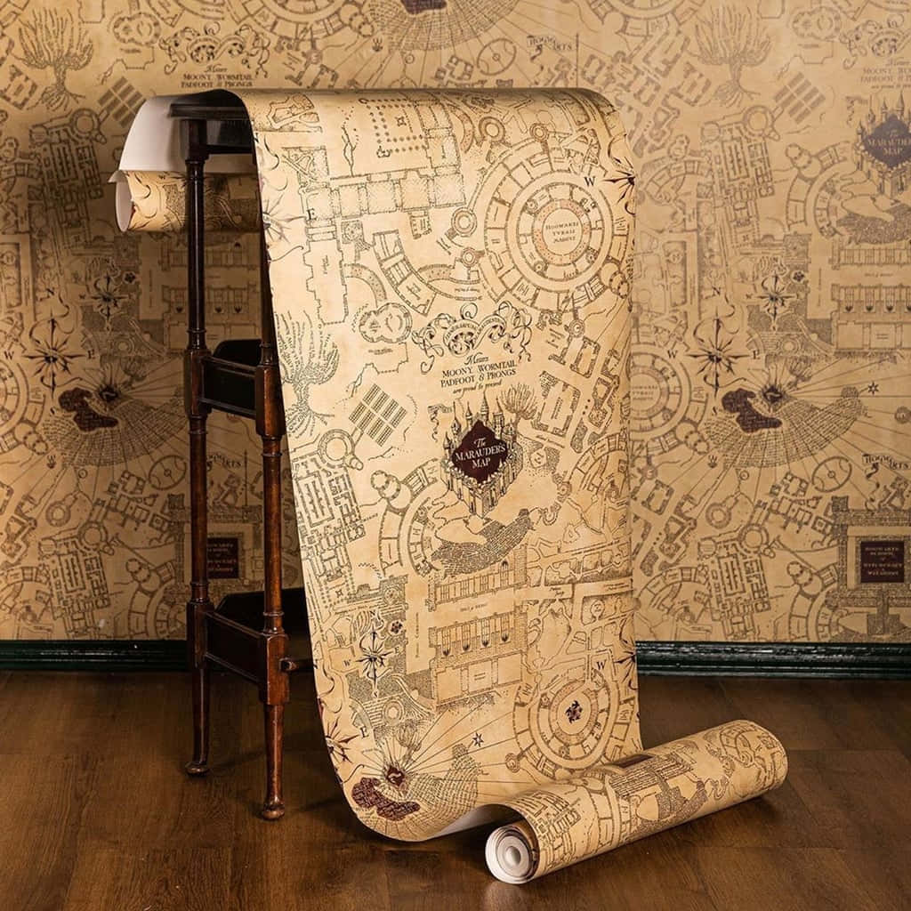 Marauders Map 桌布 壁紙 — 一張大型捲起的劫盜地圖壁紙從復古支架上展開，對著匹配的圖案牆壁。