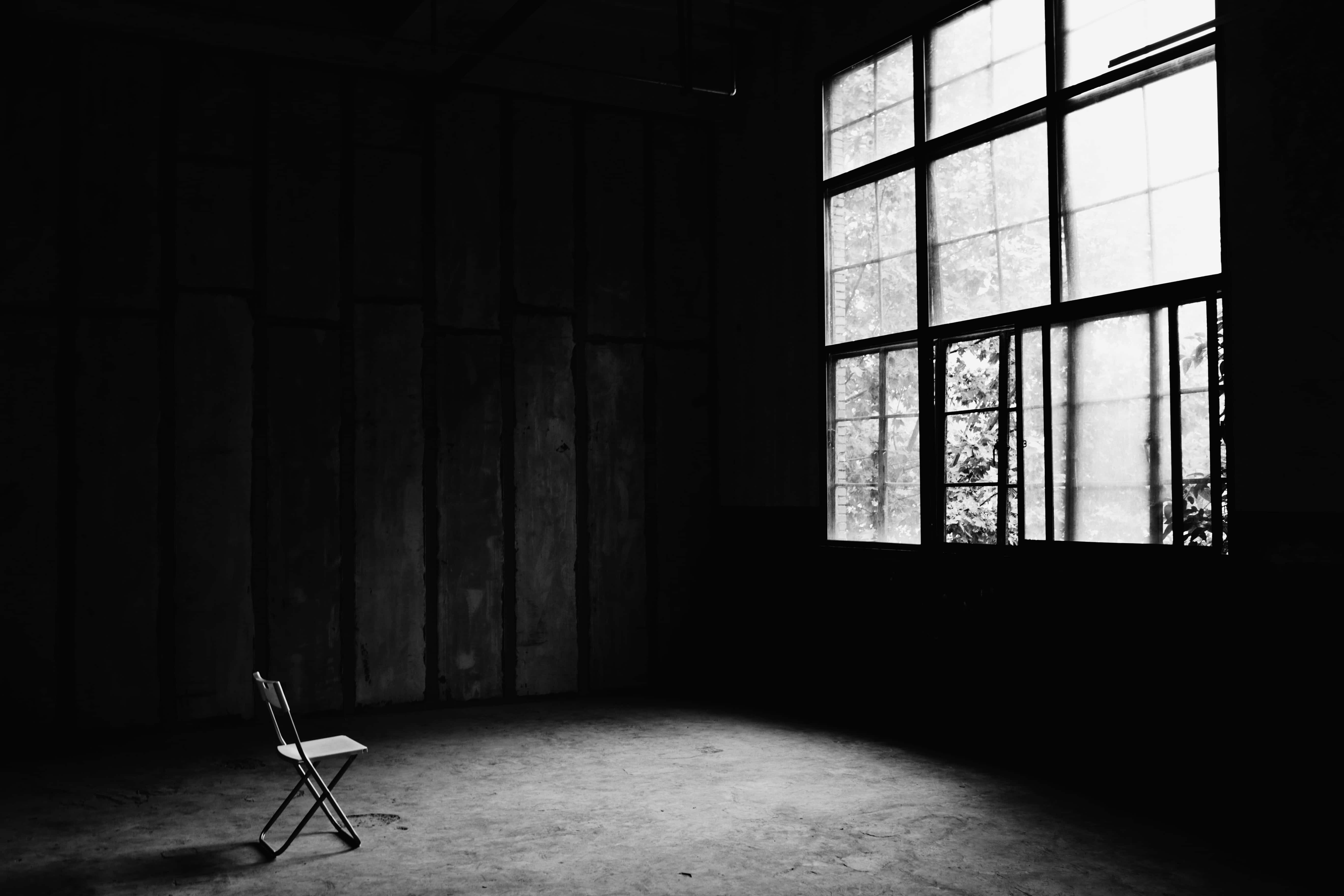 Empty Room 桌布 壁紙 — 一張孤獨的折疊椅放在昏暗廢棄的倉庫中，被大窗戶透進的強烈單色光照亮。