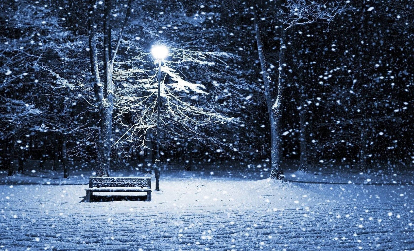 Snow Desktop 桌布 壁紙 — 一張孤獨的雪覆蓋長椅在街燈下發光，同時大雪在寧靜的冬夜公園中飄落。