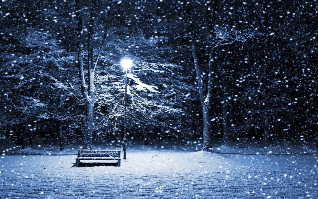 冬季桌面 桌布 壁紙 — 一張孤獨的雪覆蓋長椅在路燈下發光，夜晚的寧靜冬季公園中大雪紛飛。