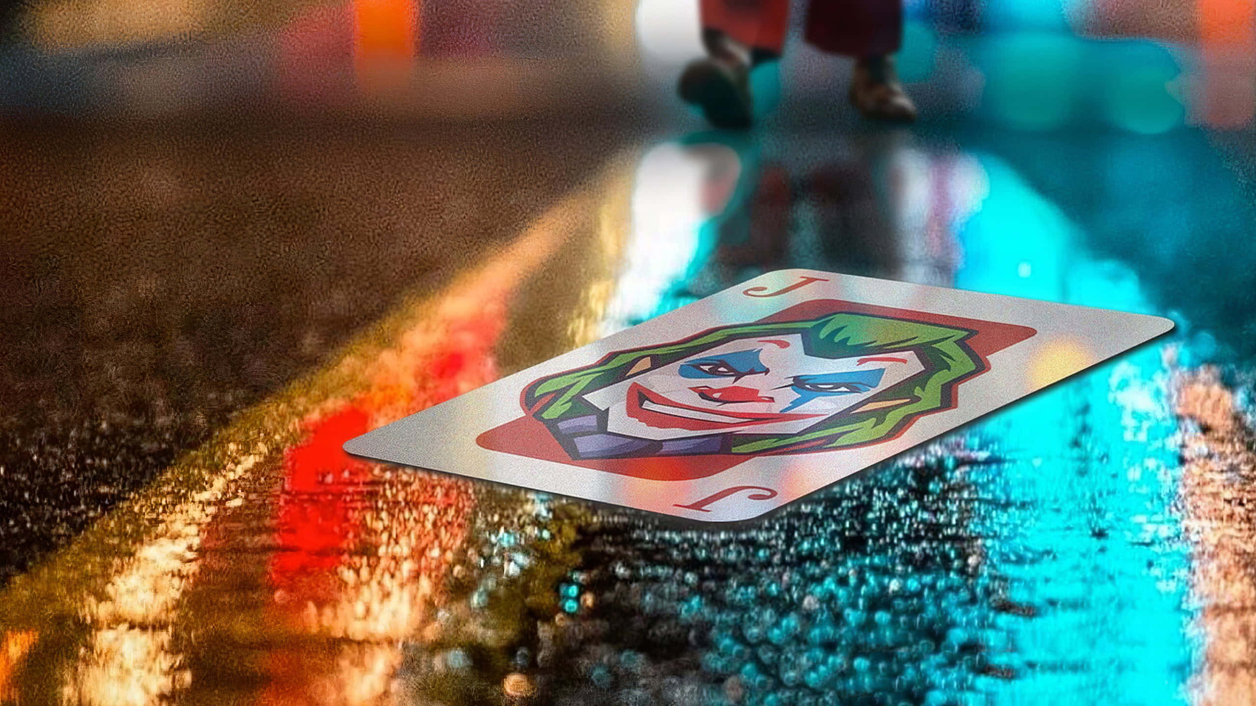 Joker Card 桌布 壁紙 — 一張小丑撲克牌放在濕漉漉的城市街道上，夜晚反射著霓虹燈光。