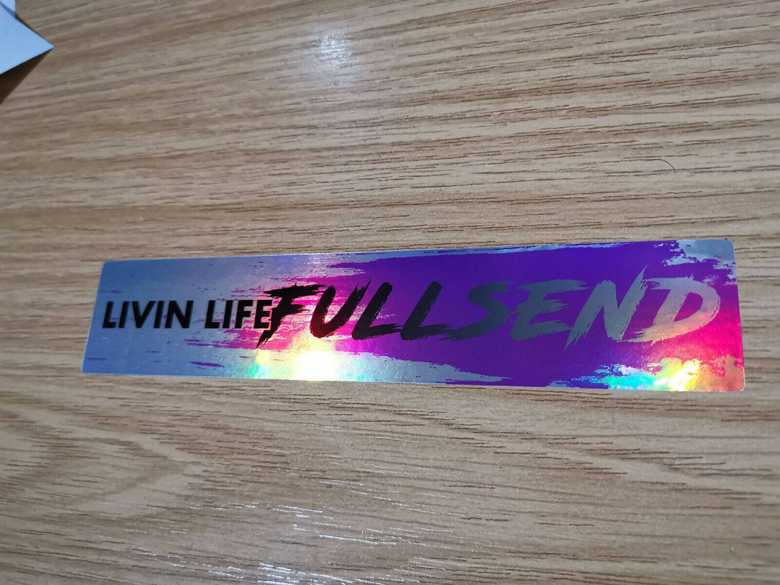 Full Send 桌布 壁紙 — 一張帶有「LIVIN LIFE FULL SEND」文字的雷射貼紙，放在淺色木紋表面上。