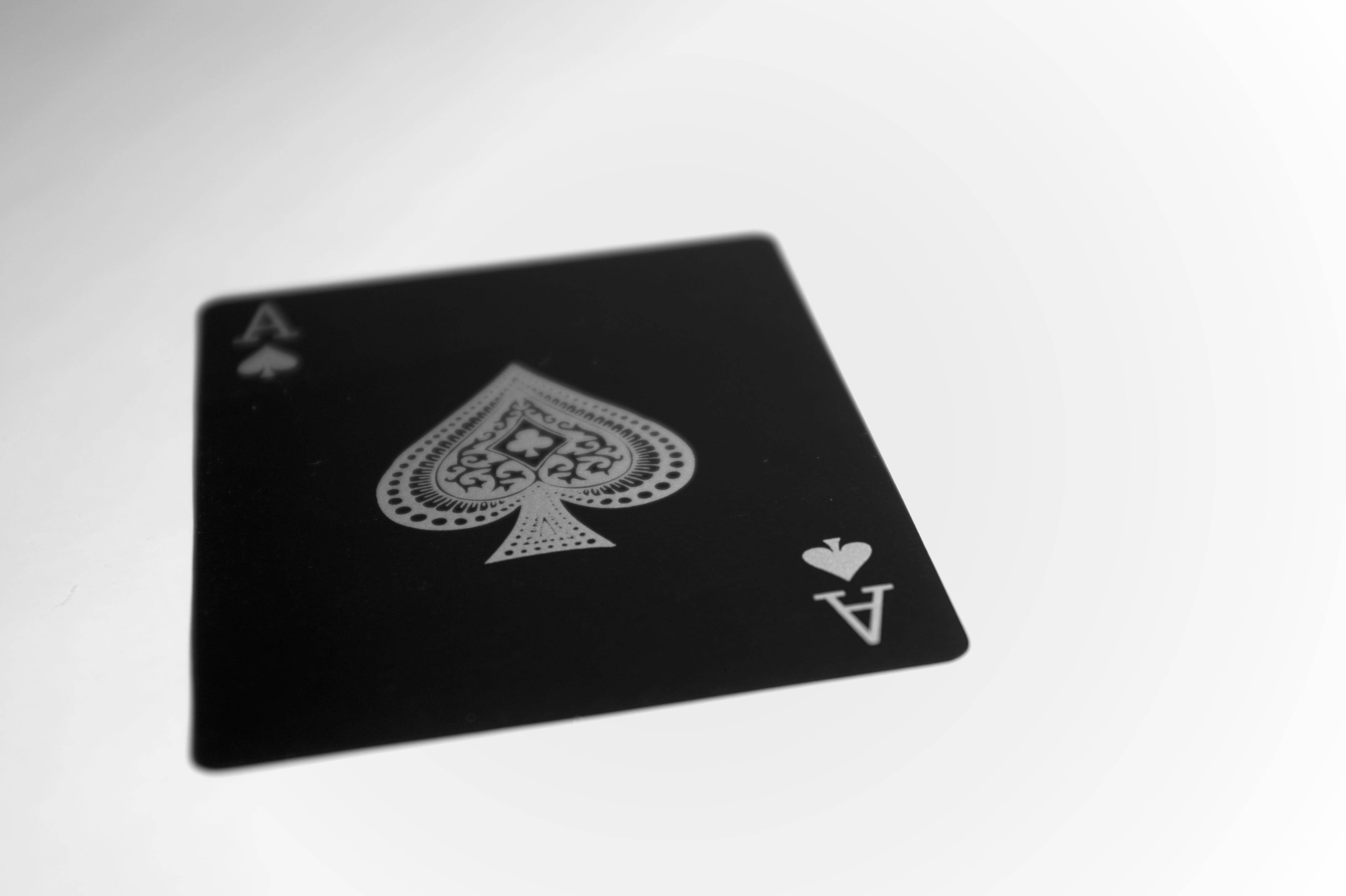 Poker 桌布 壁紙 — 一張帶有銀色細節的黑色黑桃A撲克牌放在純白色表面上。