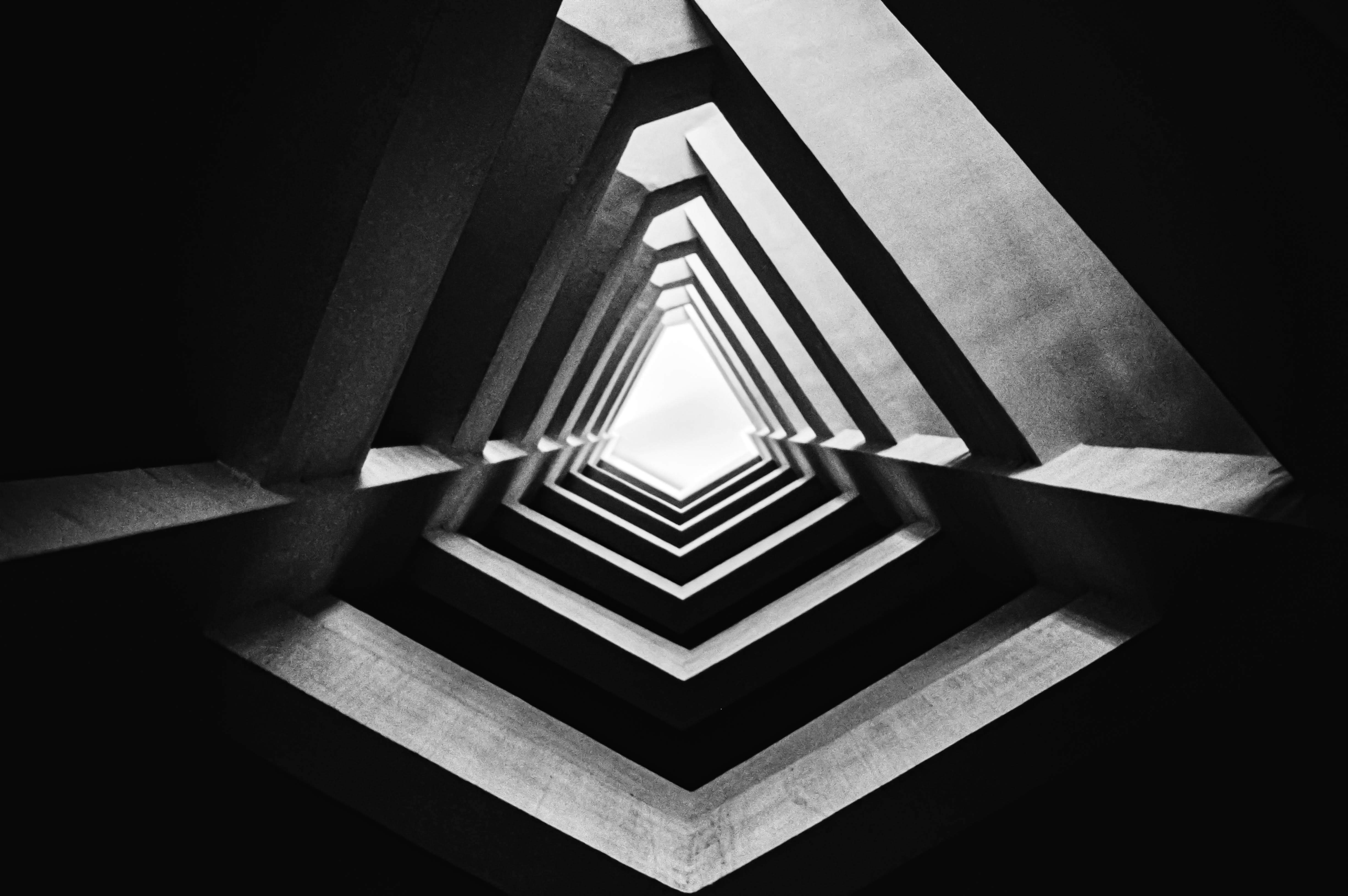 Illusion 桌布 壁紙 — 一張幾何混凝土隧道的黑白照片，三角形形狀匯聚向盡頭的明亮光線。