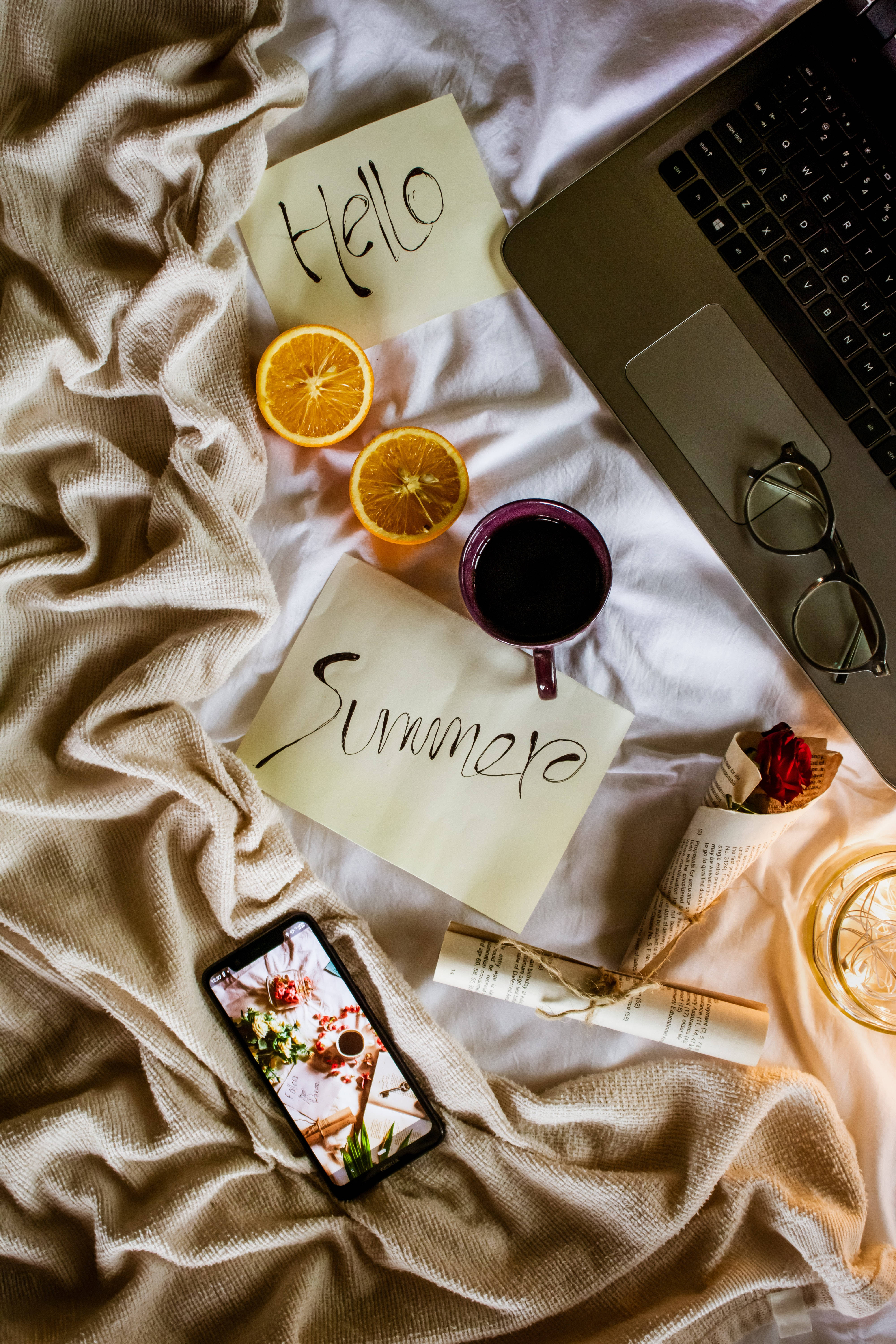 aesthetic tumblr laptop 桌布 壁紙 — 一張床的舒適俯視圖，上面有筆記型電腦、眼鏡、柳橙片、咖啡和手寫筆記，歡迎夏天的到來。