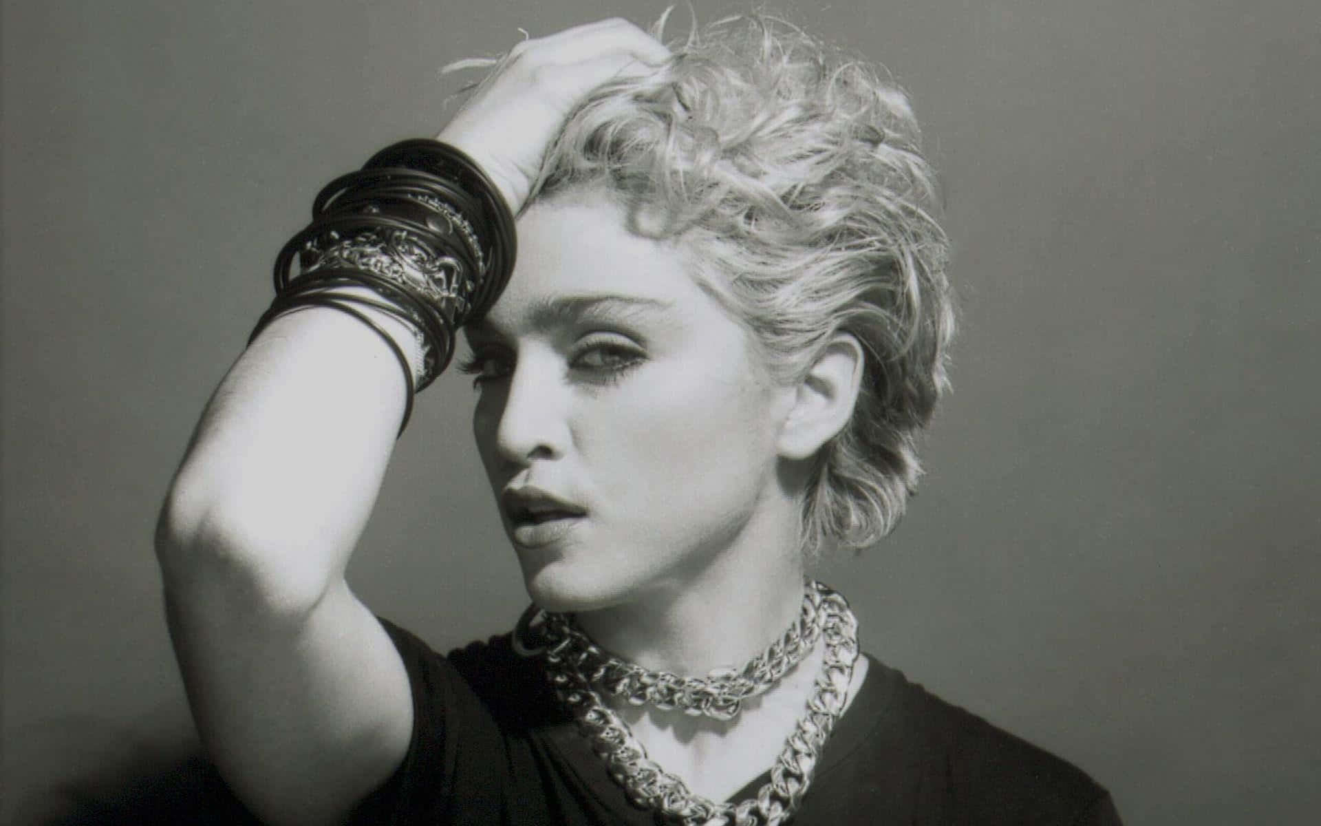 Madonna 桌布 壁紙 — 一張引人注目的瑪丹娜黑白肖像，頭髮蓬亂，佩戴大膽珠寶，一手舉至頭部。