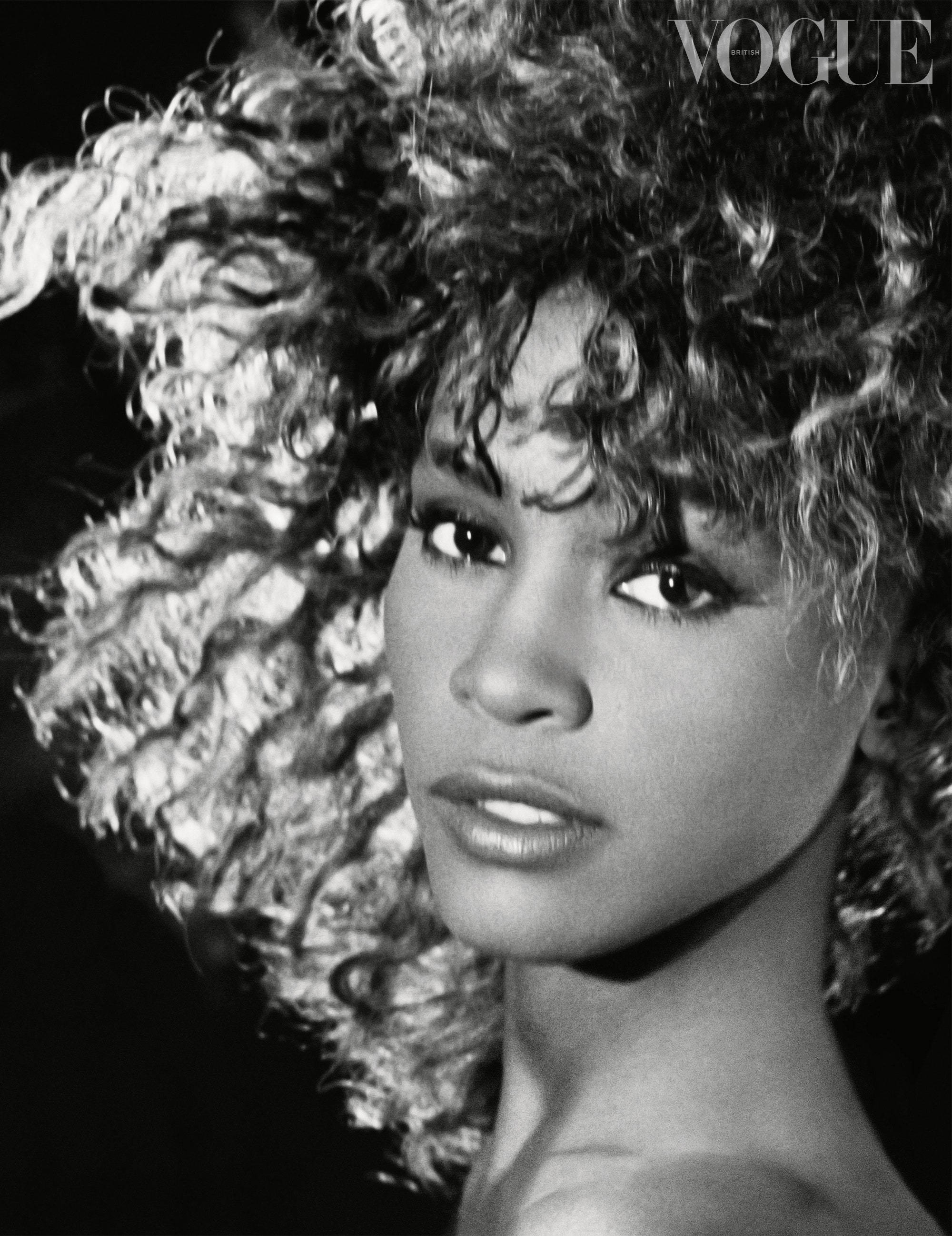 Whitney 桌布 壁紙 — 一張引人注目的黑白肖像，一位擁有豐盈捲髮的女性直視鏡頭。