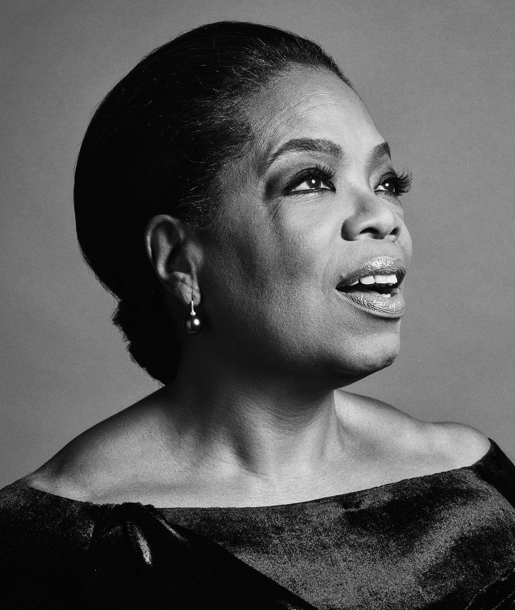 Oprah 桌布 壁紙 — 一張引人注目的黑白肖像，歐普拉·溫芙瑞向上凝視，帶著燦爛的笑容和優雅的珍珠耳環。