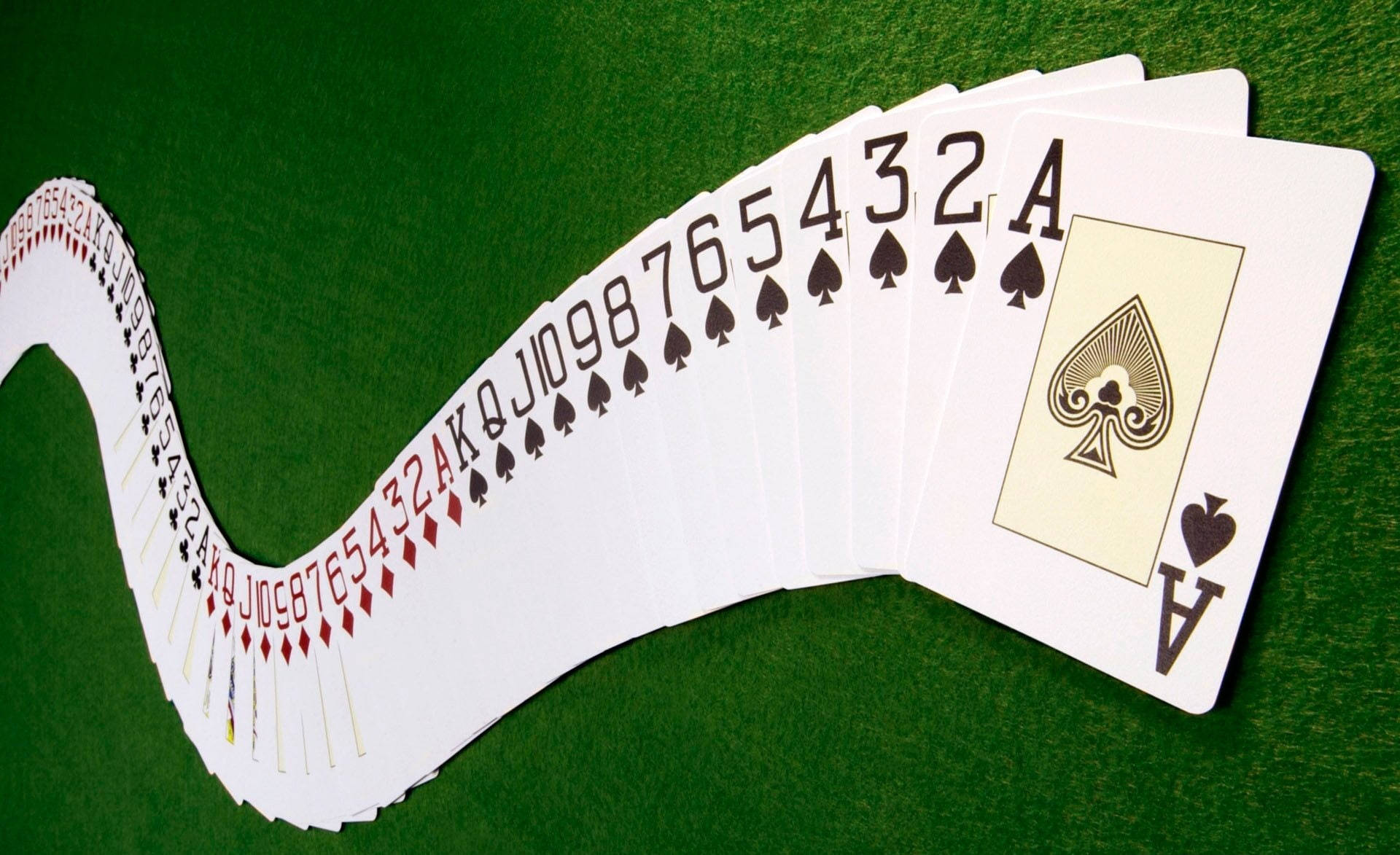 Playing Cards 桌布 壁紙 — 一張彎曲的撲克牌扇，從Ace到黑桃2，放在綠色絨面桌上。
