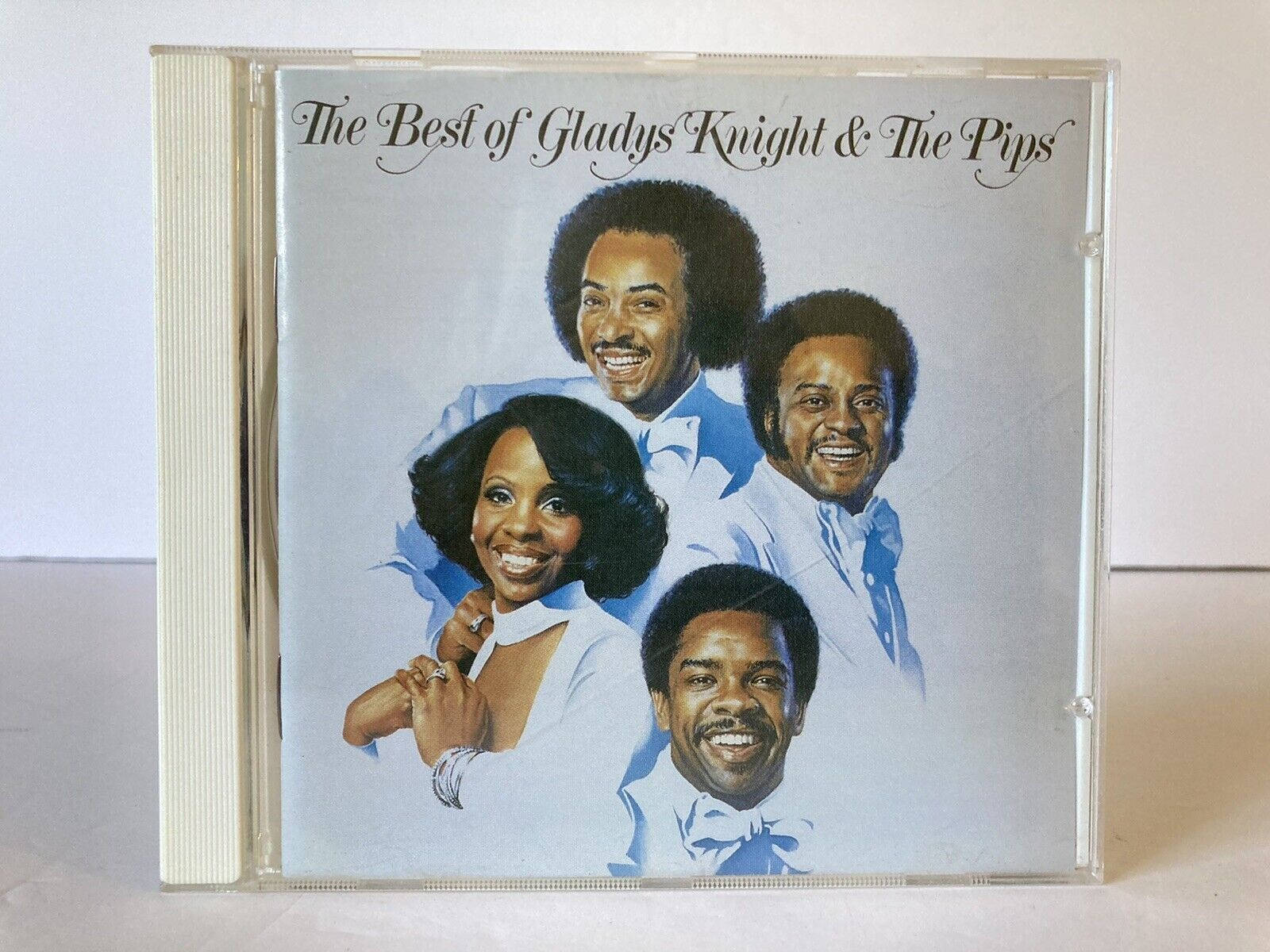 album 桌布 壁紙 — 一張復古CD封面，Gladys Knight and The Pips 穿著淺藍色西裝，在柔和的灰色背景前微笑。