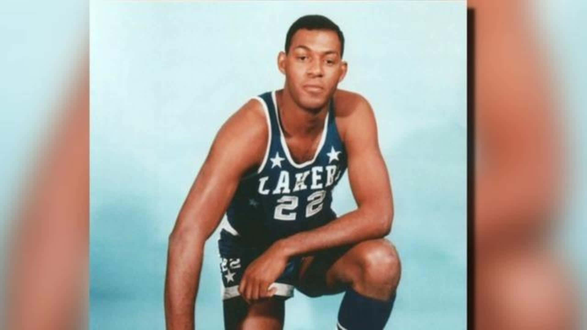 NBA 桌布 壁紙 — 一張復古工作室肖像，一名黑人籃球運動員身穿藍色湖人隊22號球衣，蹲在淺藍色背景前。