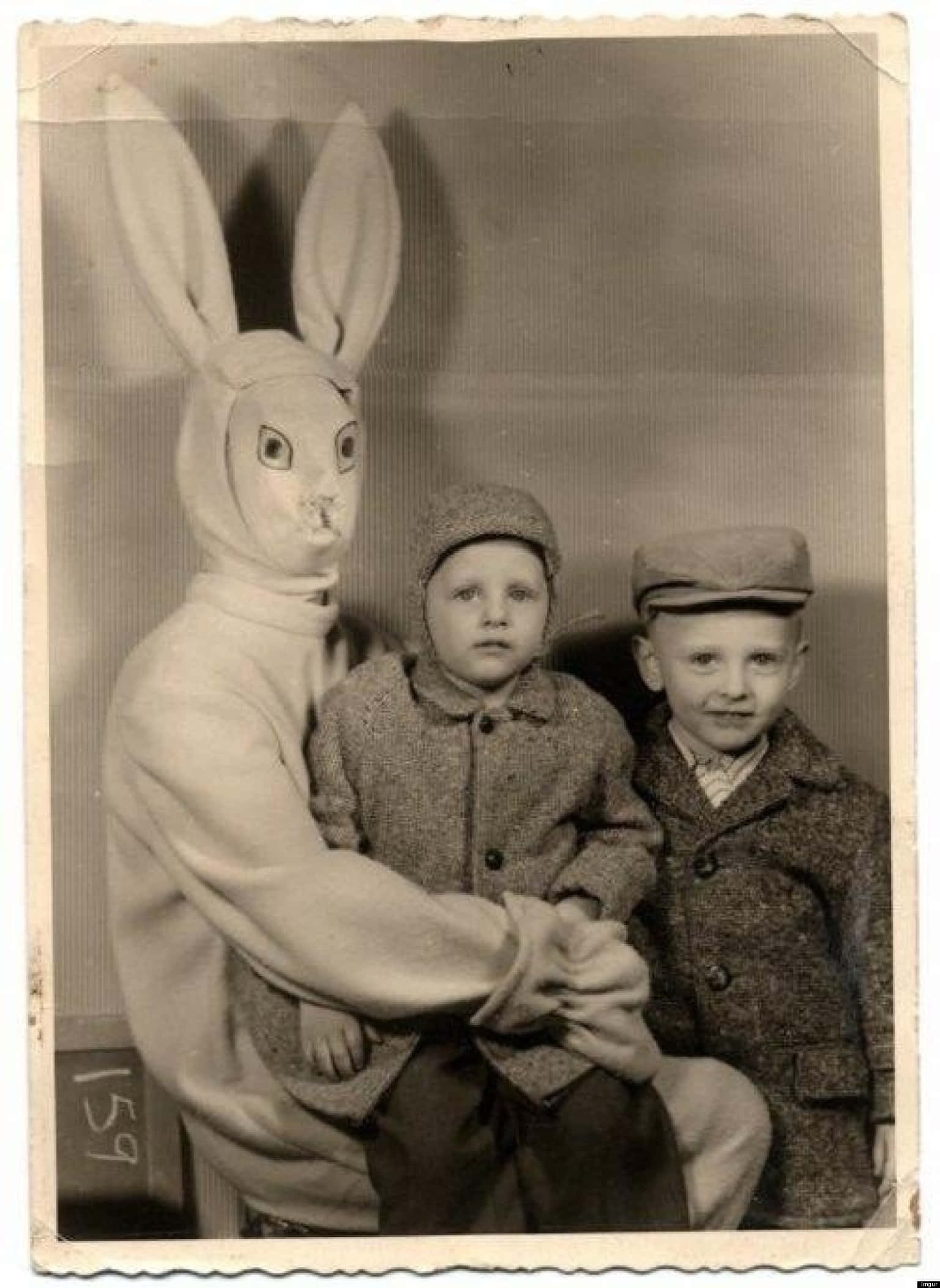 Creepy Easter Bunny 桌布 壁紙 — 一張復古棕褐色調的照片，拍攝對象穿著兔子服裝，與兩個穿著羊毛外套的小男孩手牽手。